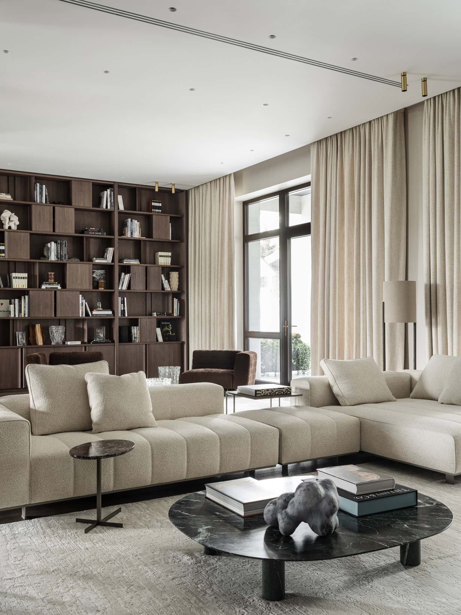 Sectional Sofa in Soft Neutral Tones Modern sectional sofa in neutral tones facing a dark wooden bookcase.