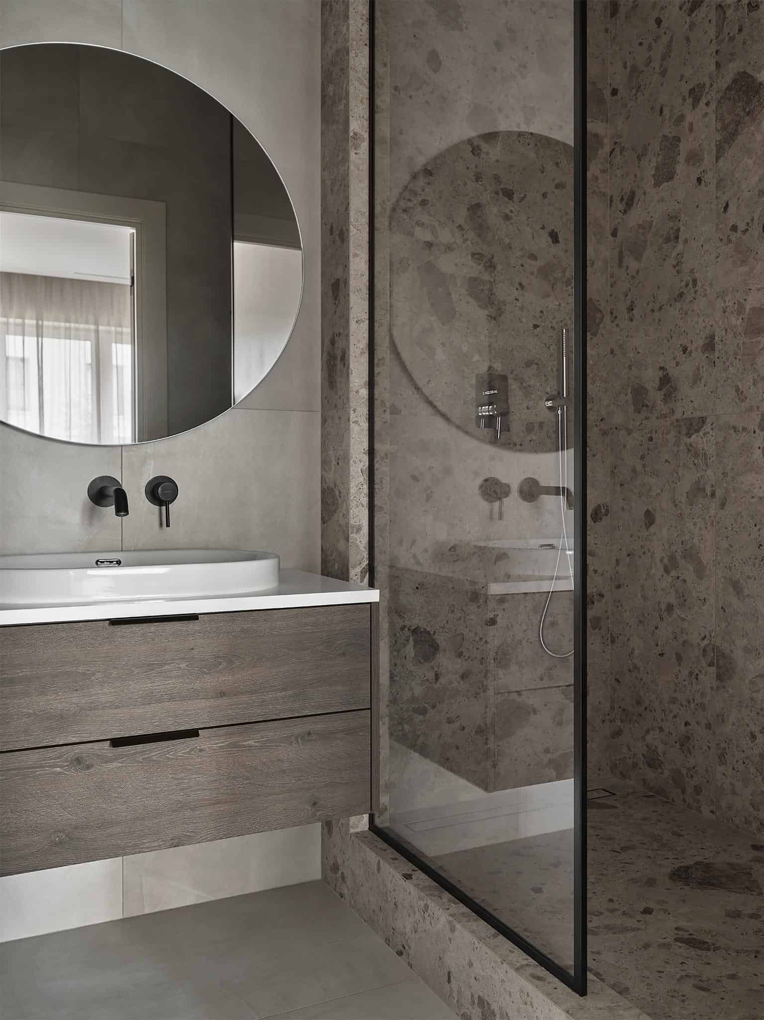 Stone Shower Enclosure and Wooden Vanity Shower enclosure with textured stone walls and wooden vanity with black fixtures.