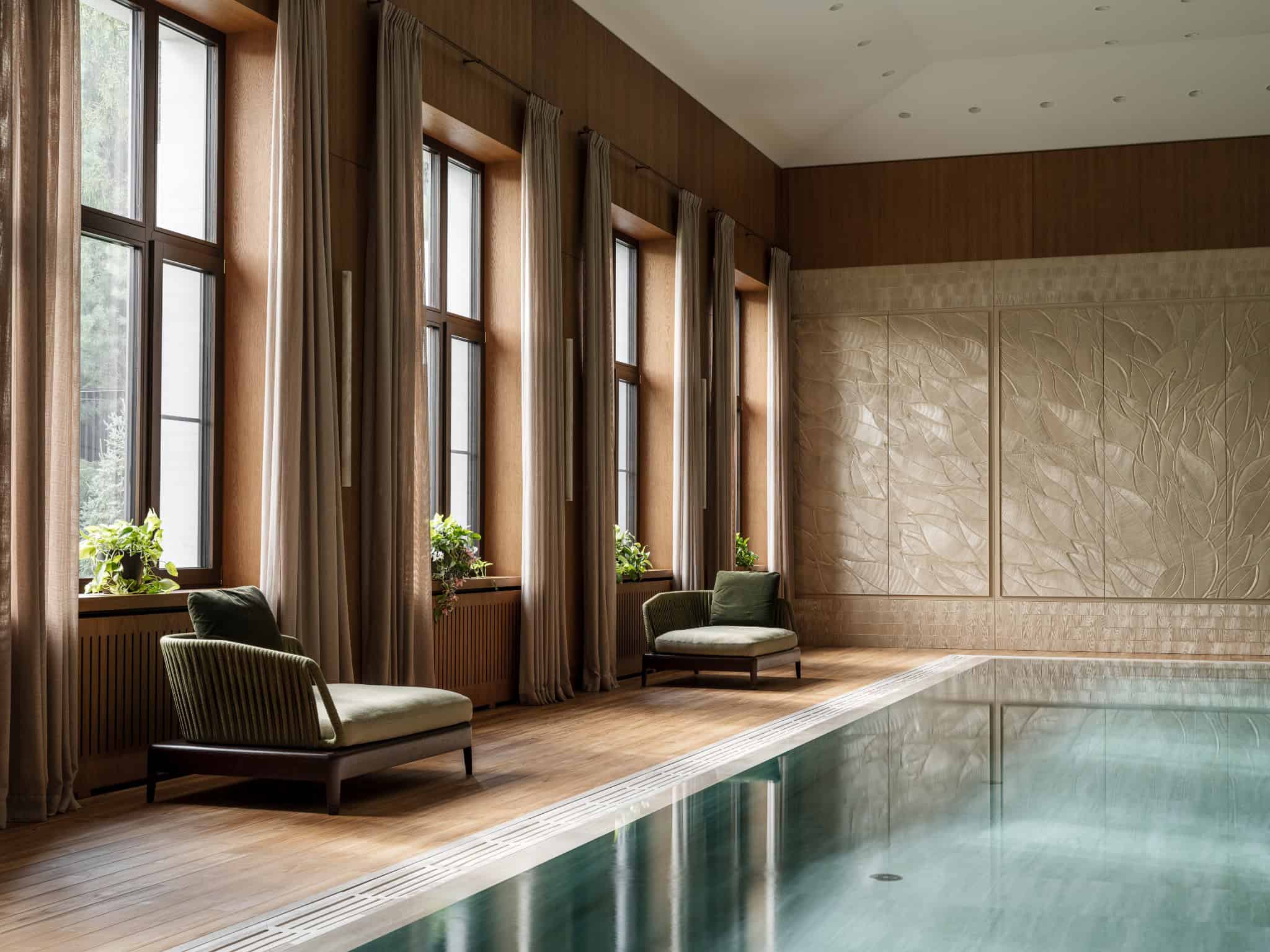 Sunlit Poolside Lounge with Green Chairs Lounge chairs by the poolside basking in natural light from tall windows.