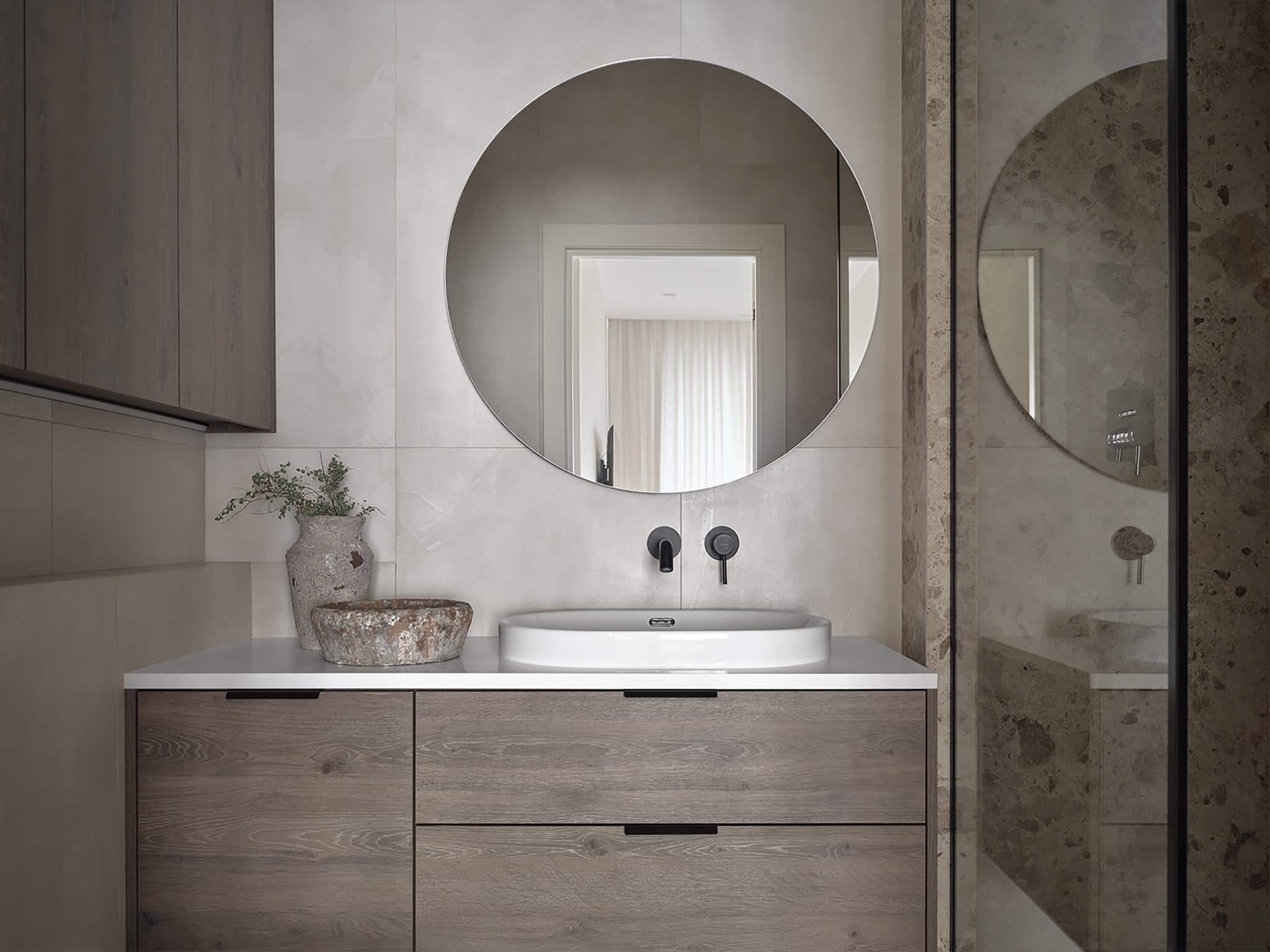 Textured Bathroom Design with Round Mirror Textured bathroom wall with wood vanity, round mirror, and neutral tones.