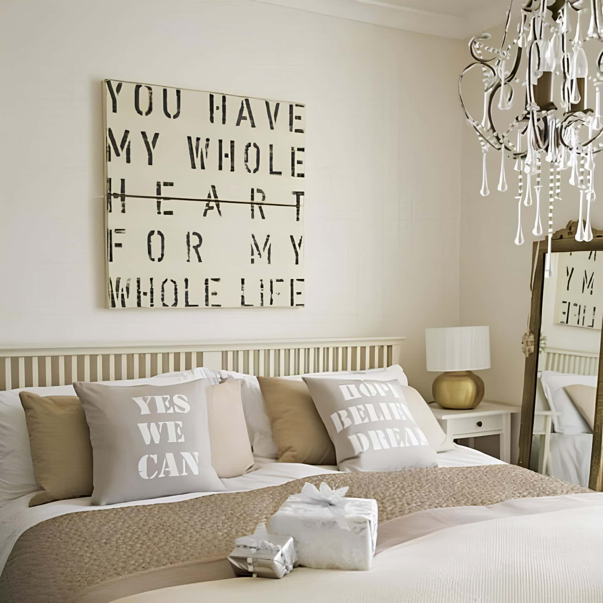 Romantic wall art with stenciled quote above a neutral-toned bed with typography pillows.
