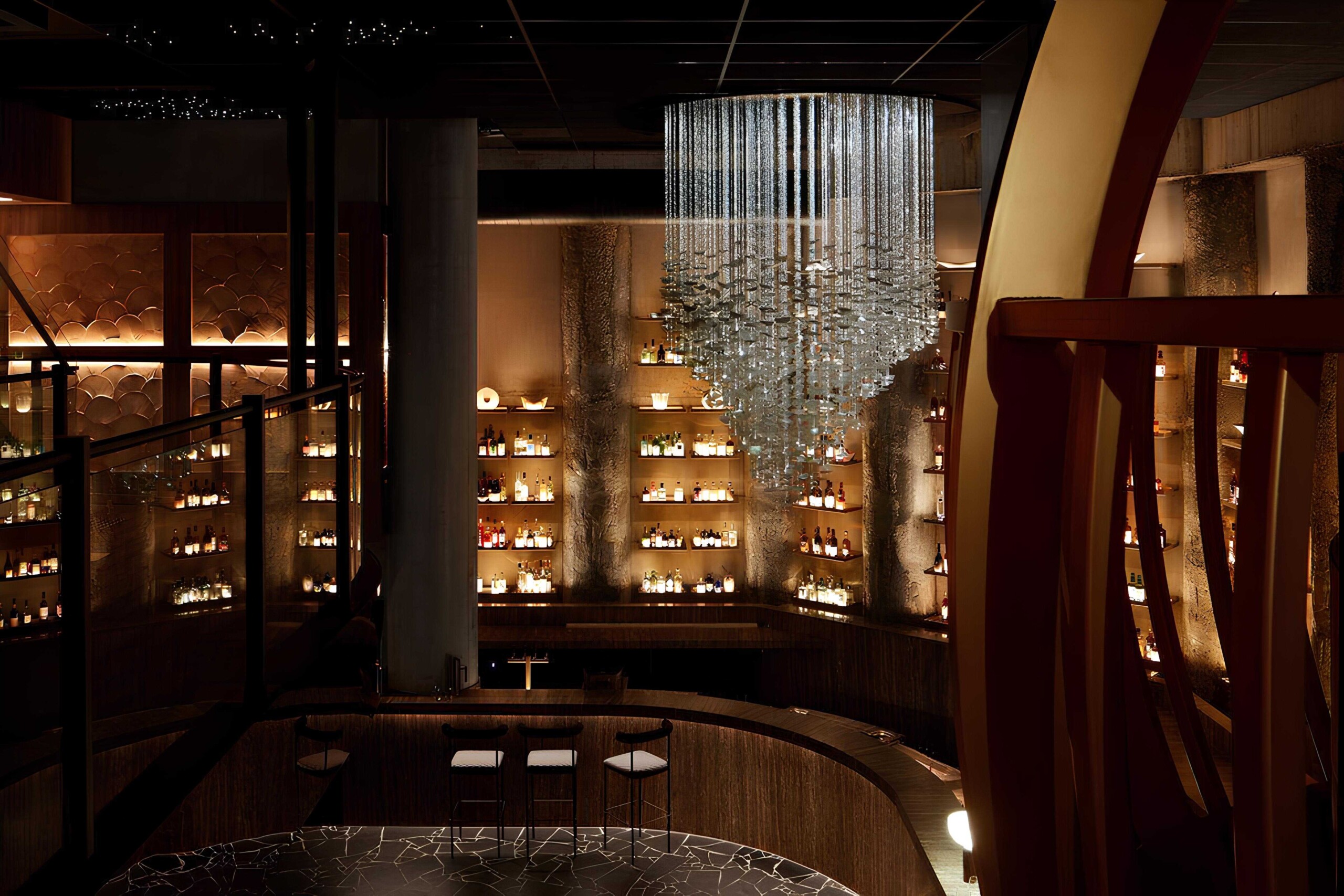 Luxury modern bar interior with a stunning chandelier, warm ambient lighting, and sophisticated wooden decor for upscale restaurant design.