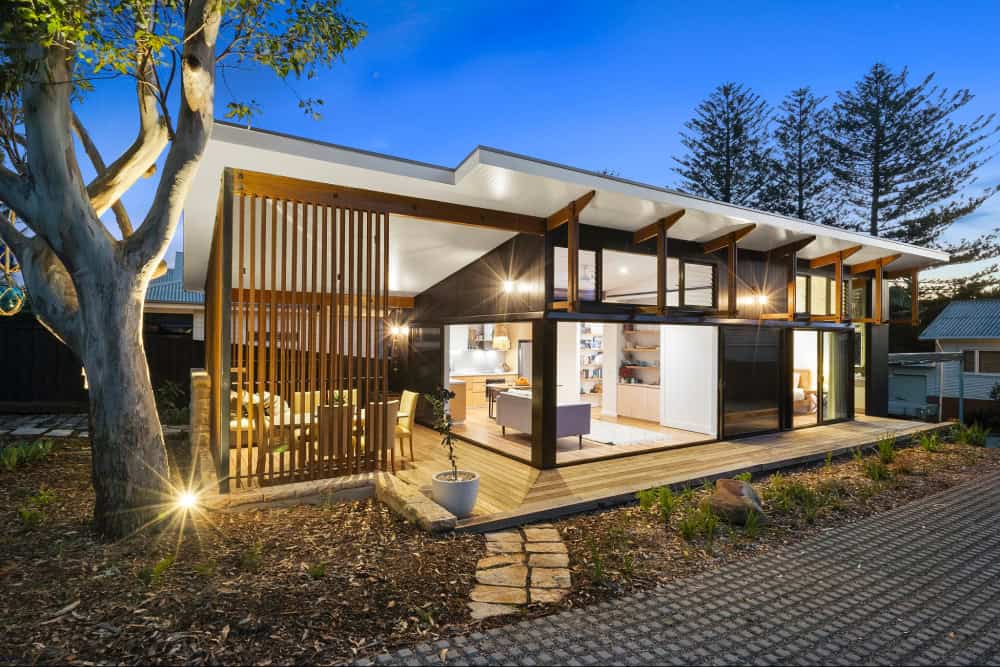 Modern Flat Roof House with Open-Plan Living and Wooden Deck Modern flat roof house with open-plan living and timber deck illuminated at dusk