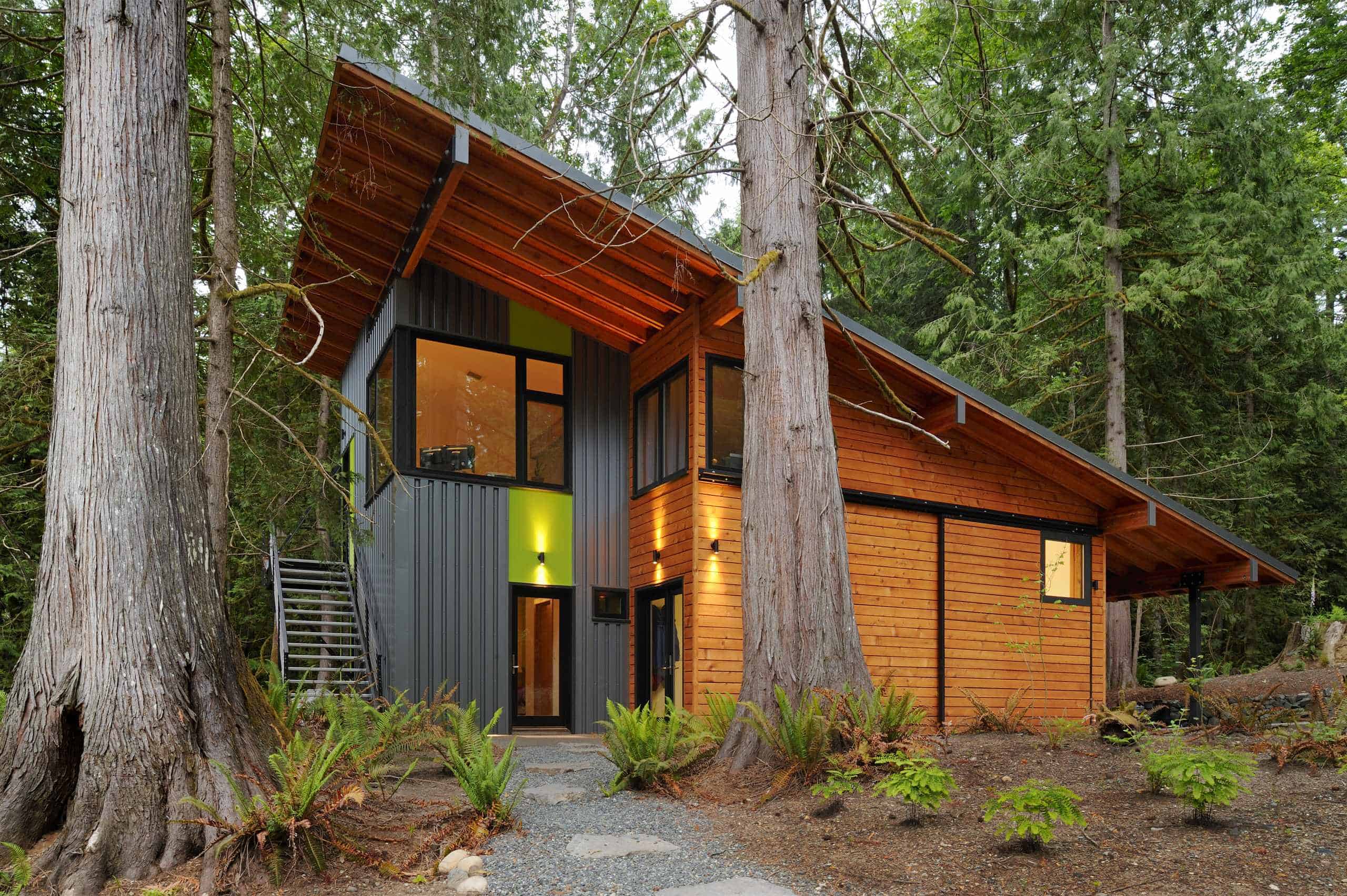Modern Wood Cabin in Forest with Shed Roof Modern forest cabin with wood and metal facade, large windows, and shed-style roof