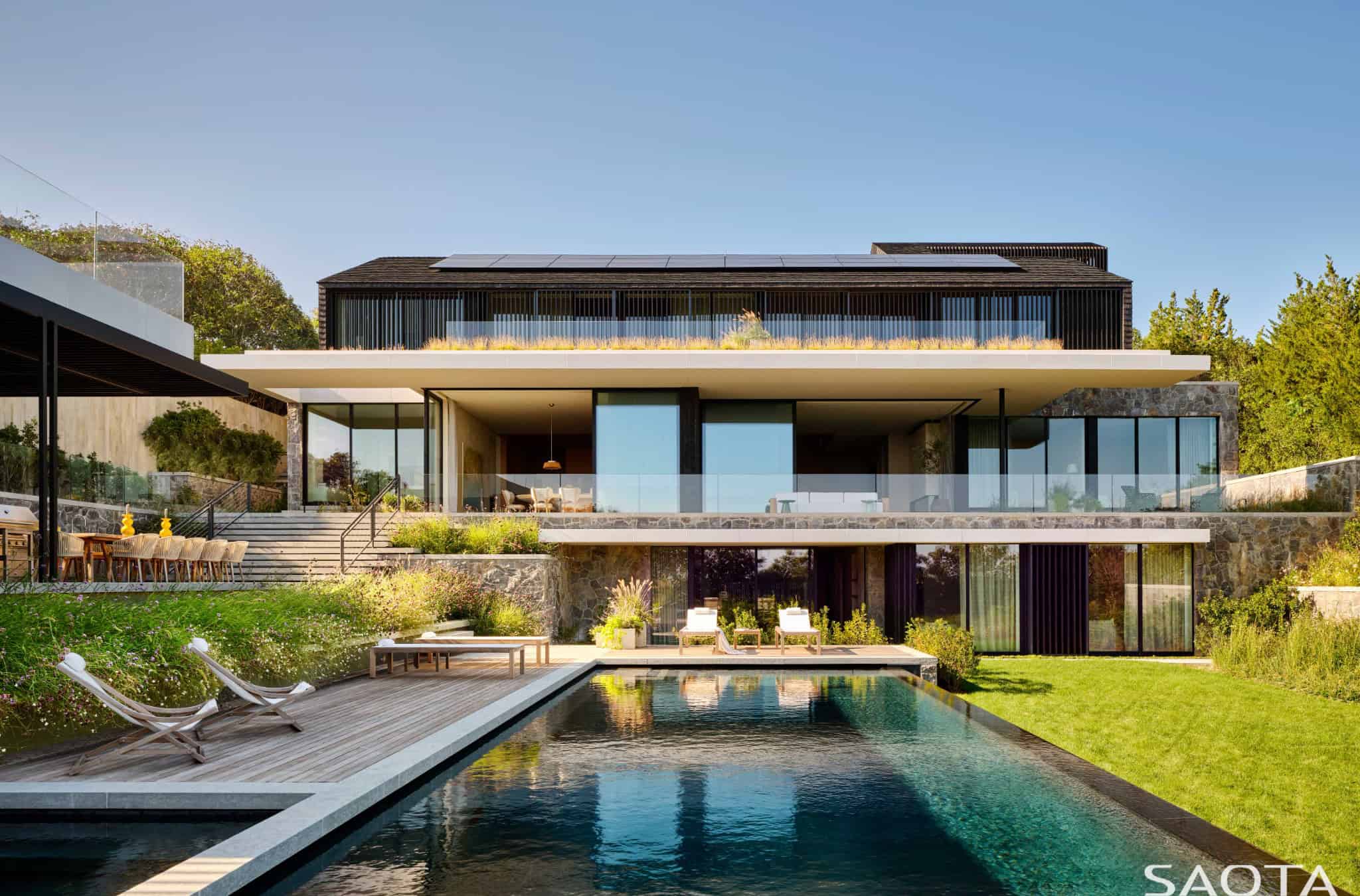 Luxurious modern house with sleek architectural design, large glass windows, infinity pool, and landscaped garden, perfect for contemporary architecture and luxury home design enthusiasts.