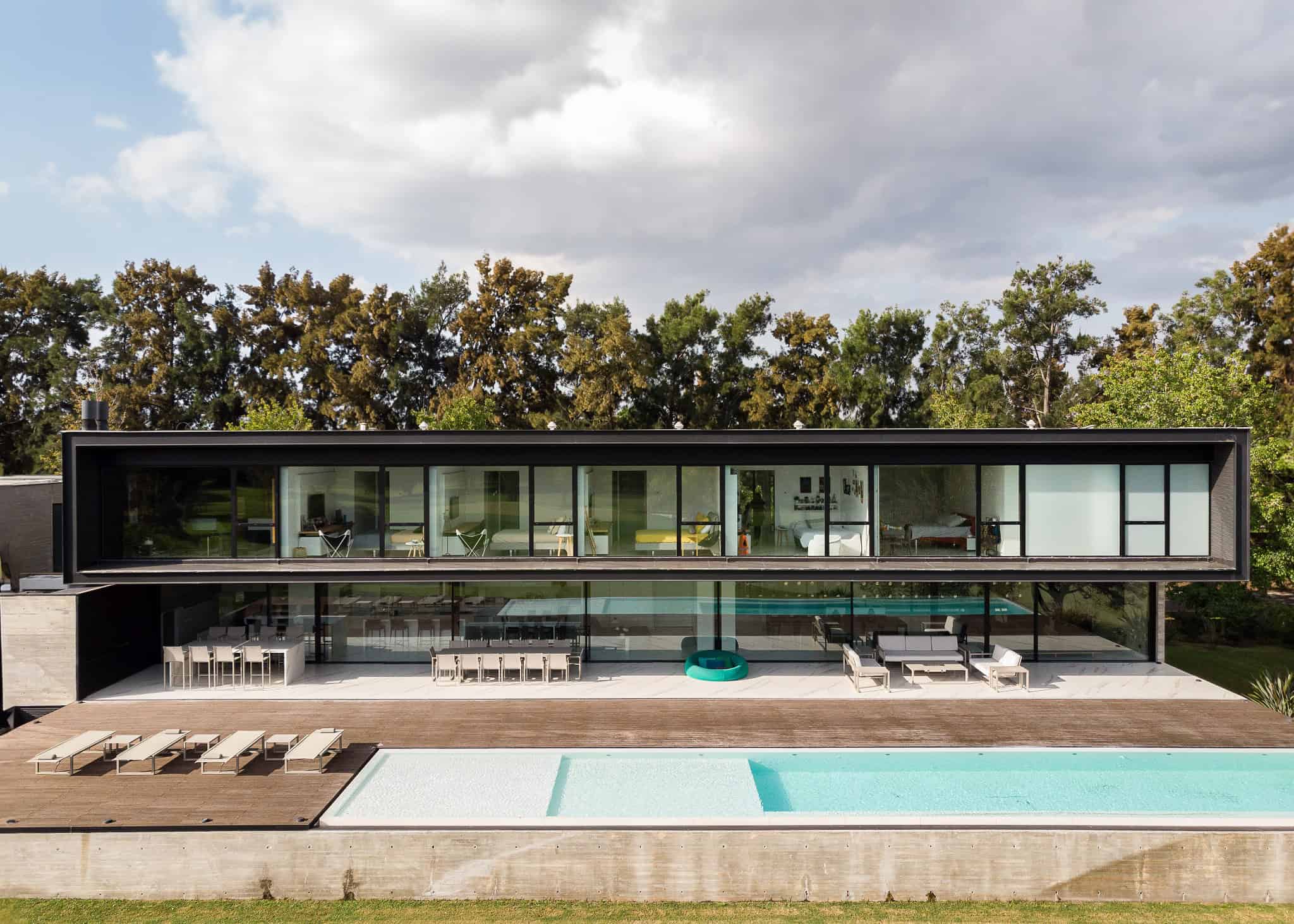 Pacheco House by A4estudio 03 Full frontal view of Pacheco House with large windows and pool.
