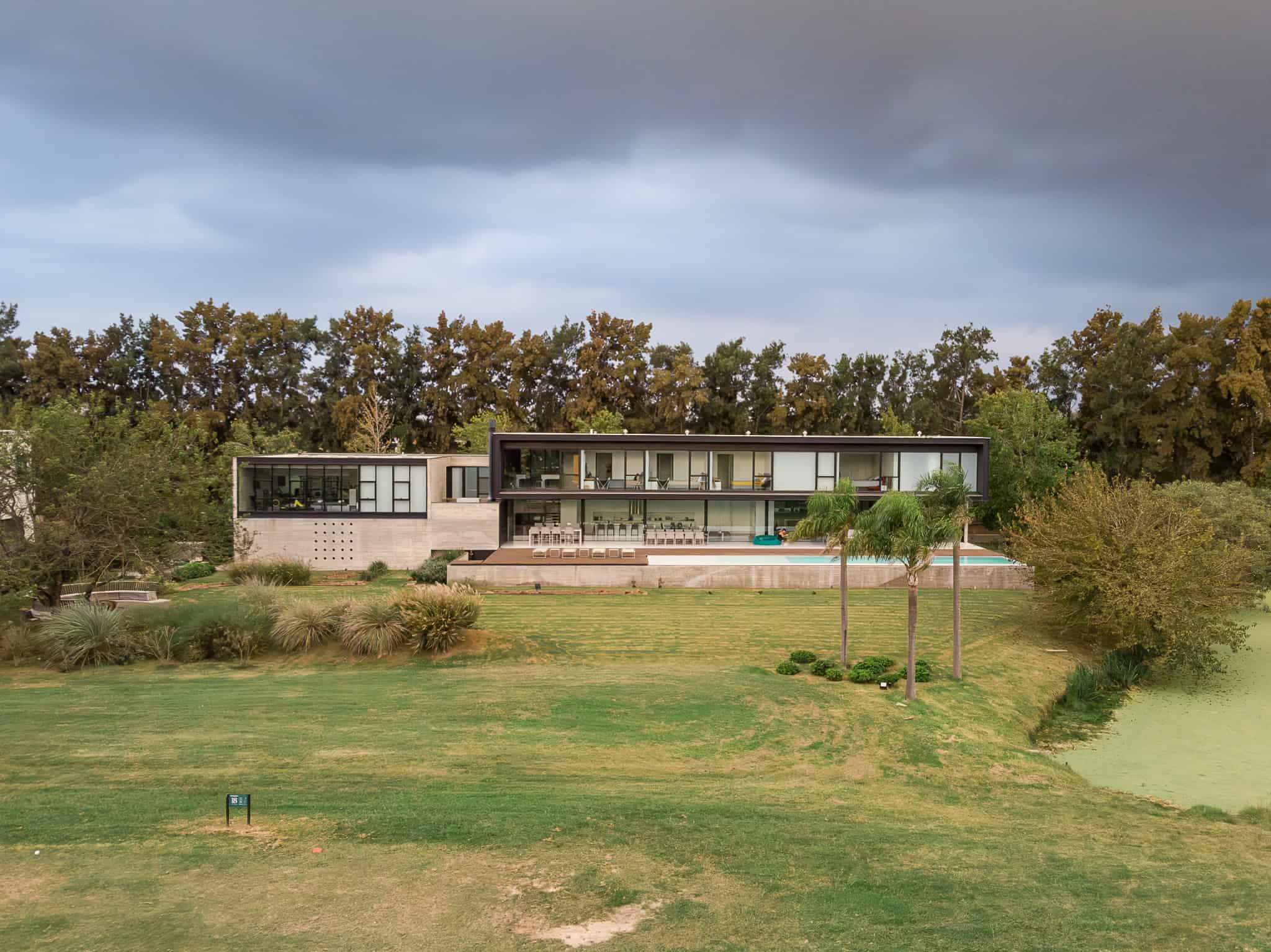 Pacheco House by A4estudio 09 Panoramic view of the entire house framed by trees and lawn.