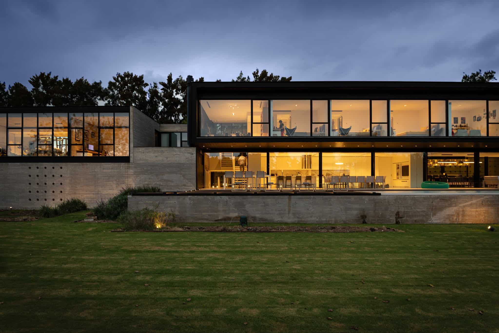 Pacheco House by A4estudio 11 Close-up of living and dining areas glowing at dusk.