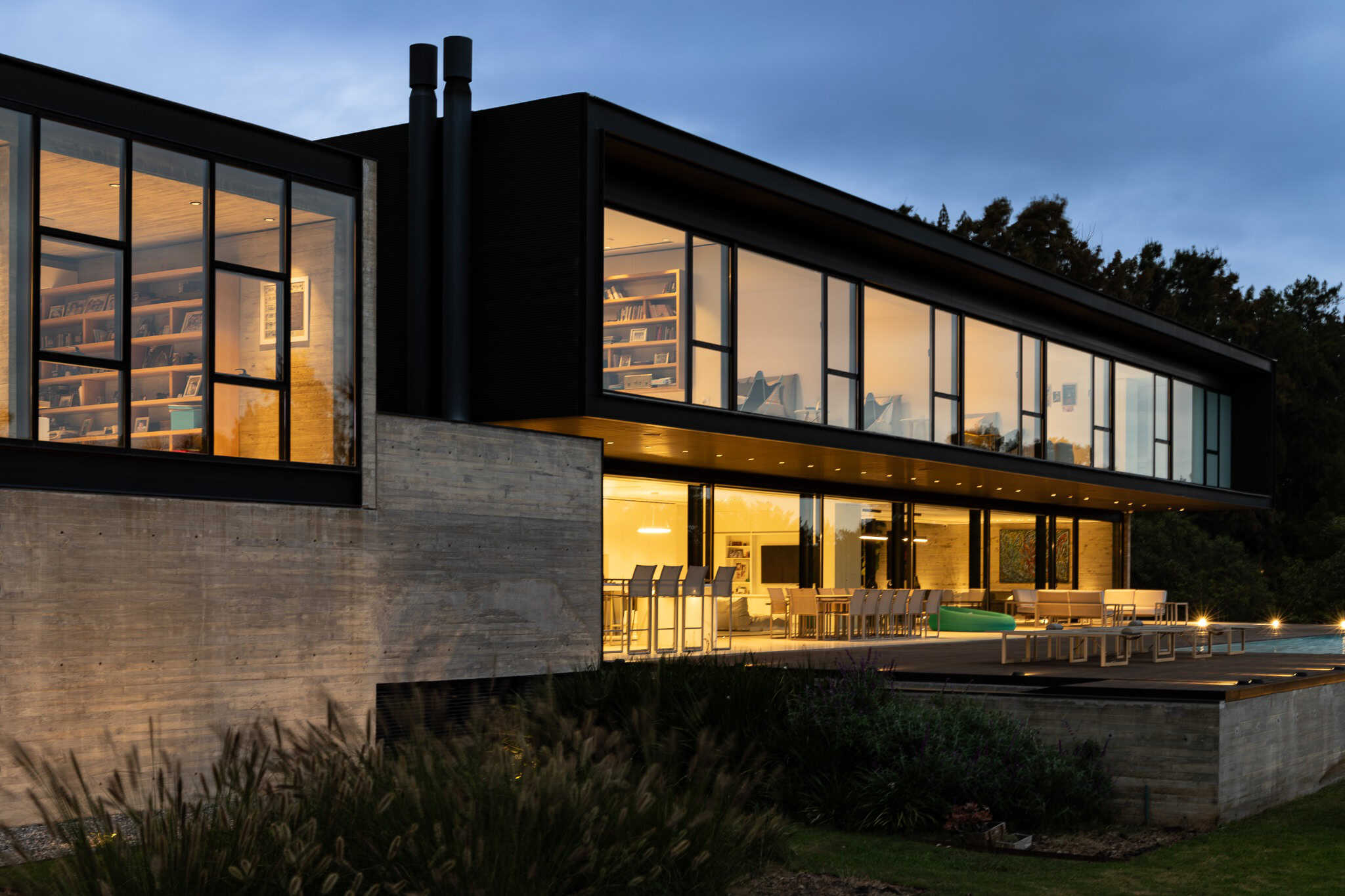Pacheco House by A4estudio 14 Perspective of the modern concrete home glowing warmly at night.