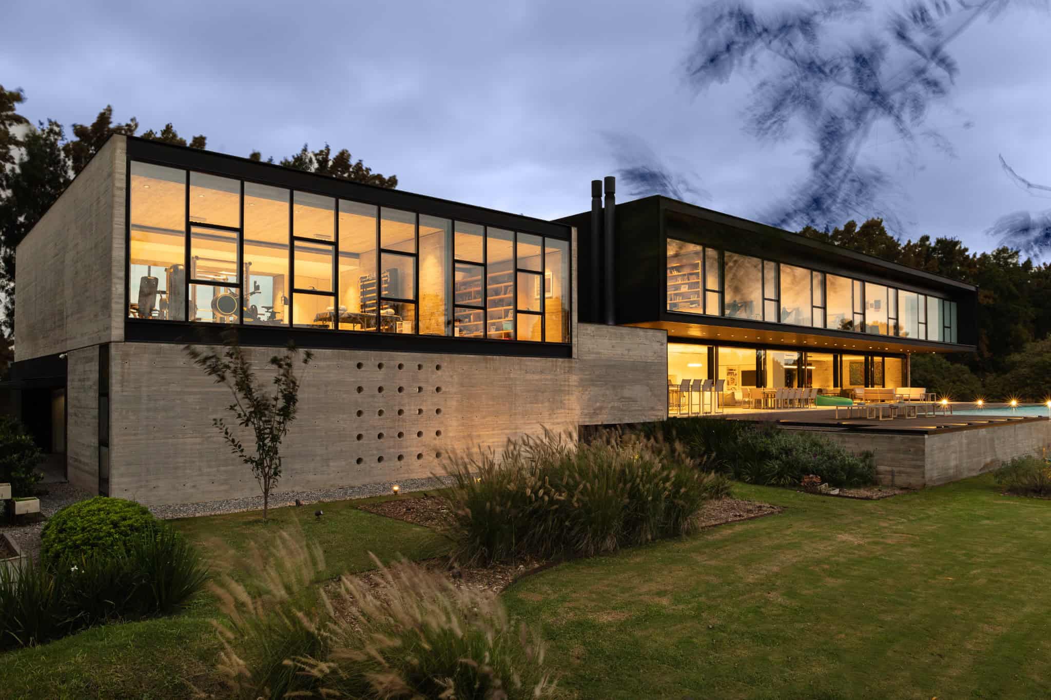 Pacheco House by A4estudio 15 Side view showing gym and library wing at twilight.