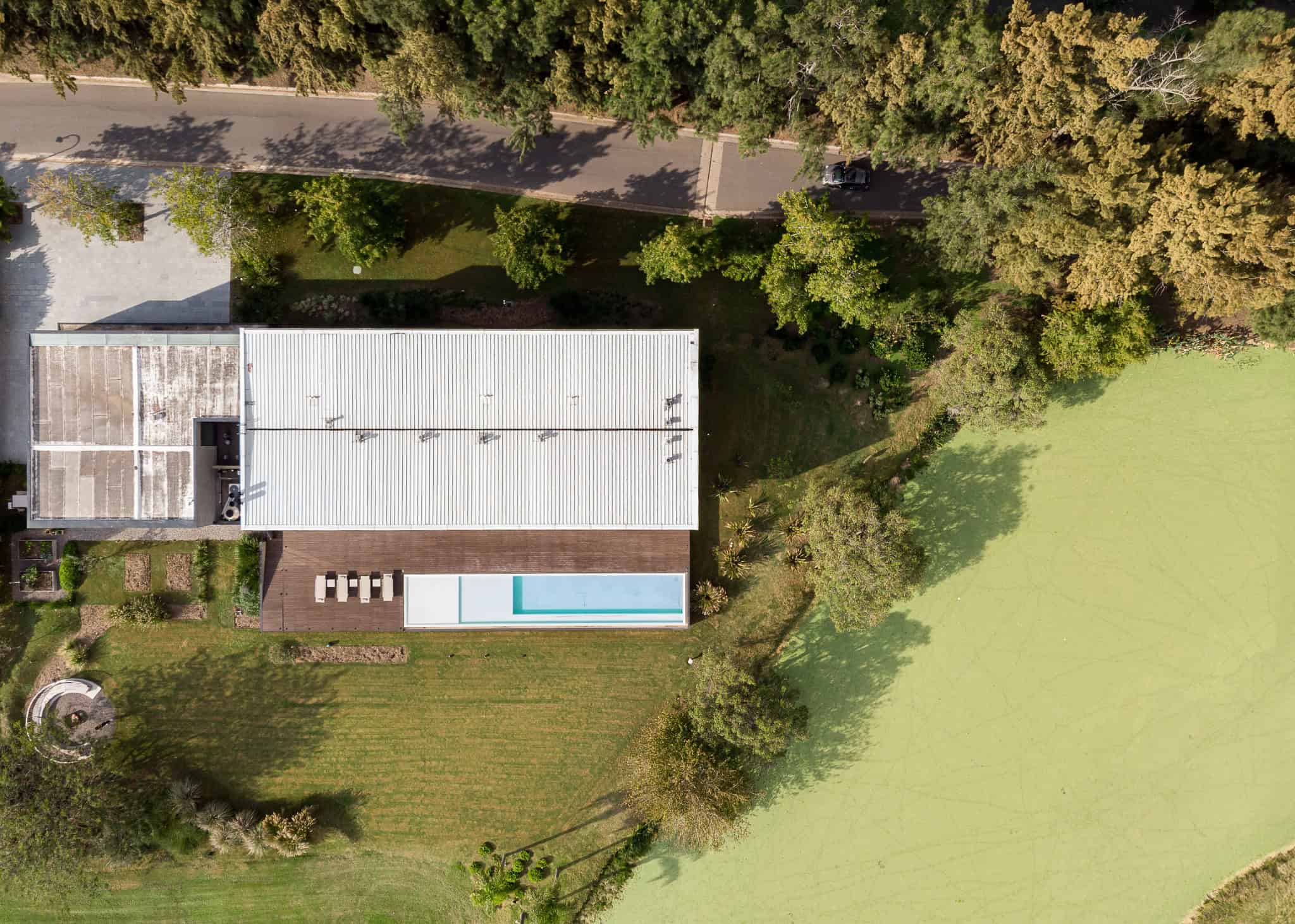 Pacheco House by A4estudio 16 Aerial view of Pacheco House surrounded by green landscape and pond.