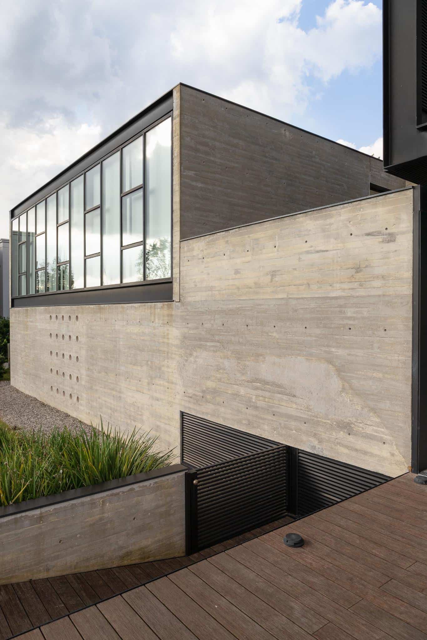 Detail of Pacheco House corner facade with perforated concrete and large vertical glazing.