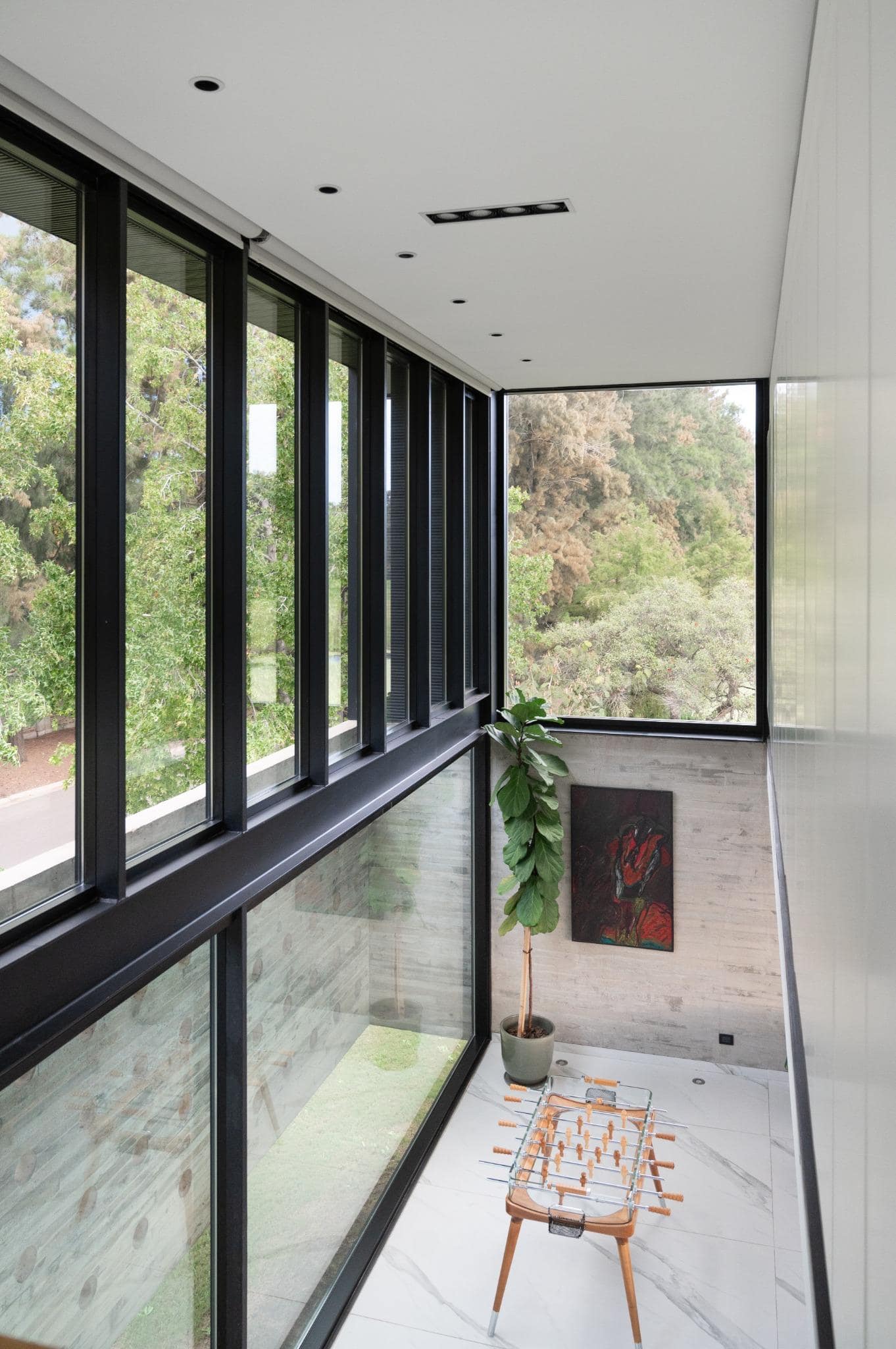 Pacheco House Corner Window Games Room Games corner at Pacheco House featuring foosball table and full-height corner window with views of greenery.