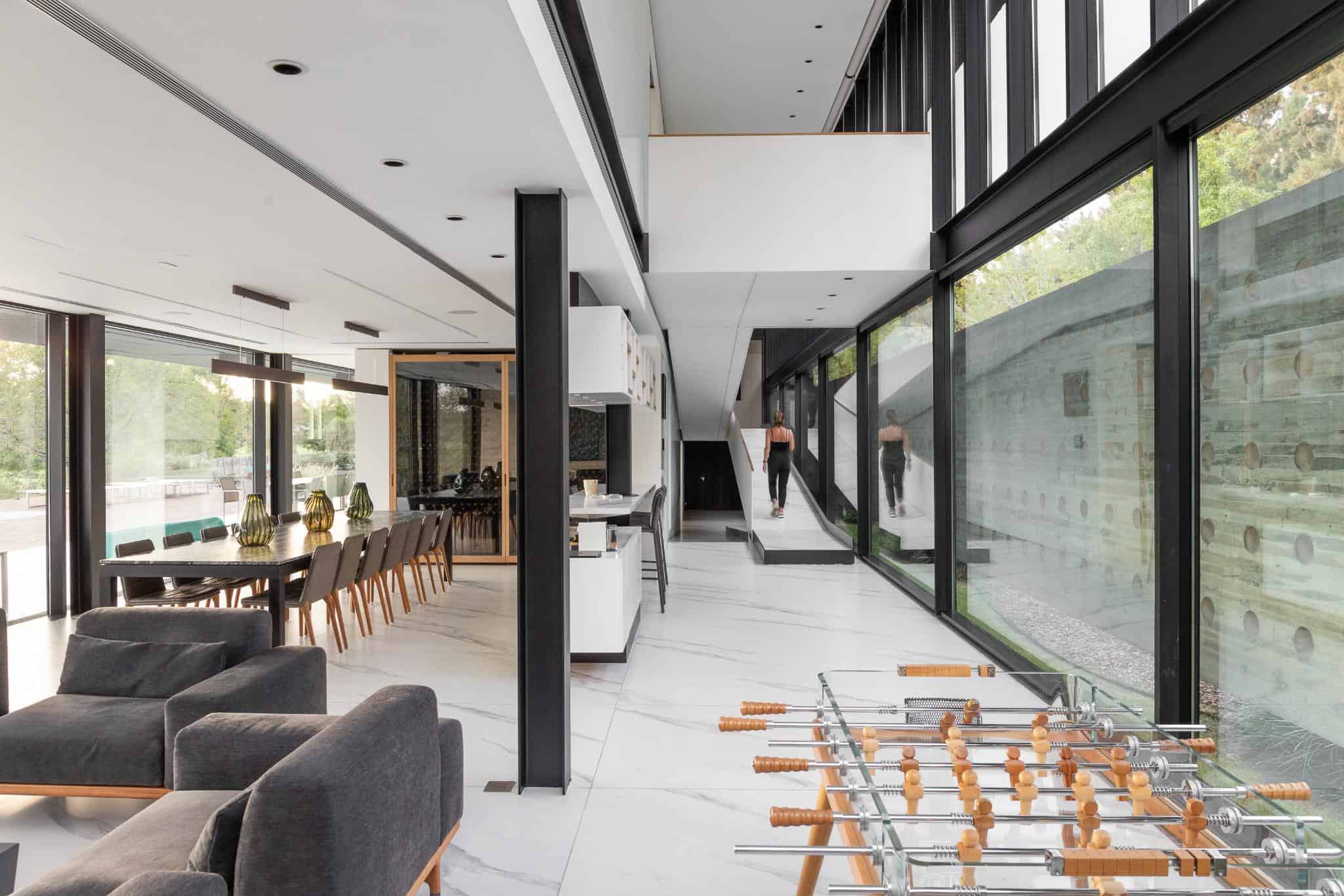 Pacheco House Dining Area Double Height Space Open-plan dining and living area in Pacheco House with large windows and foosball table.