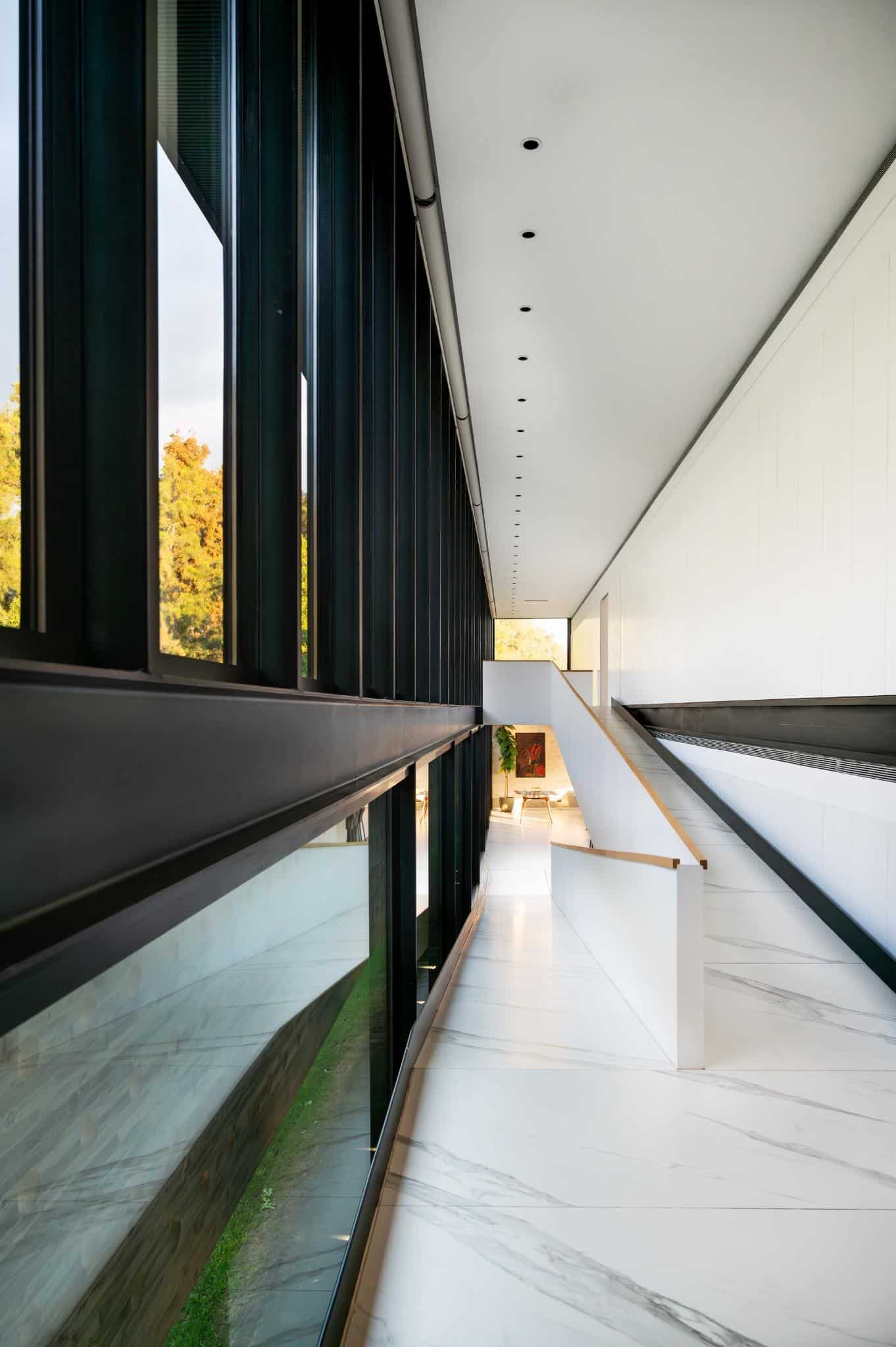 Pacheco House Glass Corridor Morning Light Pacheco House corridor bathed in soft morning light, flanked by black steel window framing.