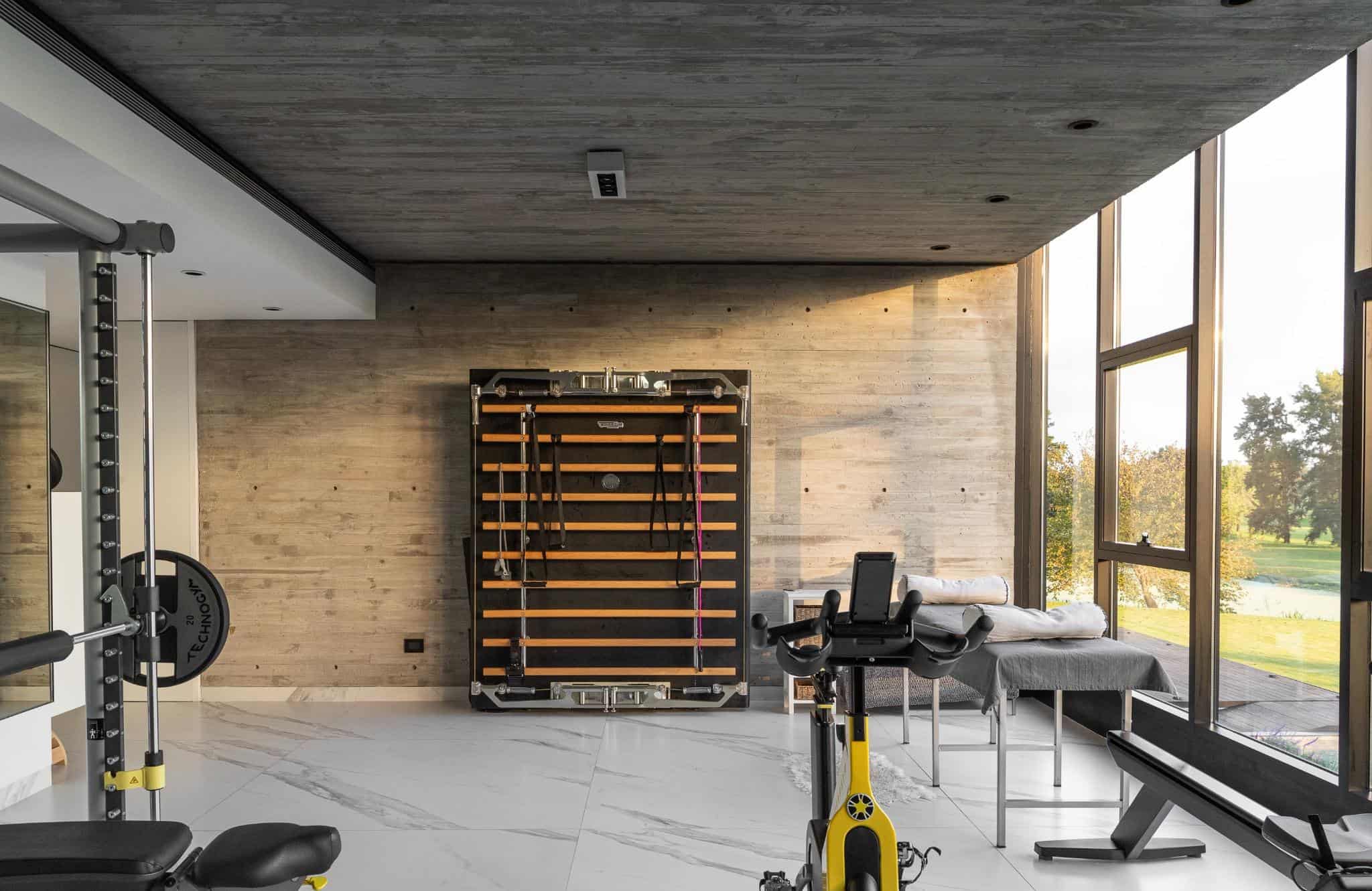 Pacheco House Gym Wall Training Station Home gym area in Pacheco House with Technogym wall trainer and raw concrete wall.