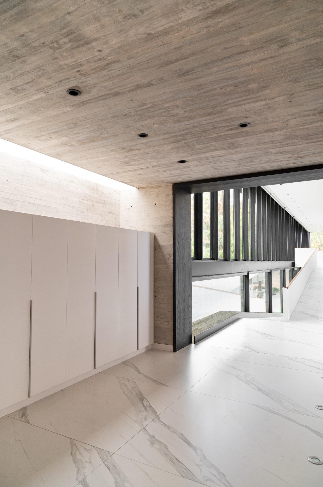 Pacheco House Interior Light and Texture Combination of raw concrete ceiling and minimalist cabinetry in the interior of Pacheco House.