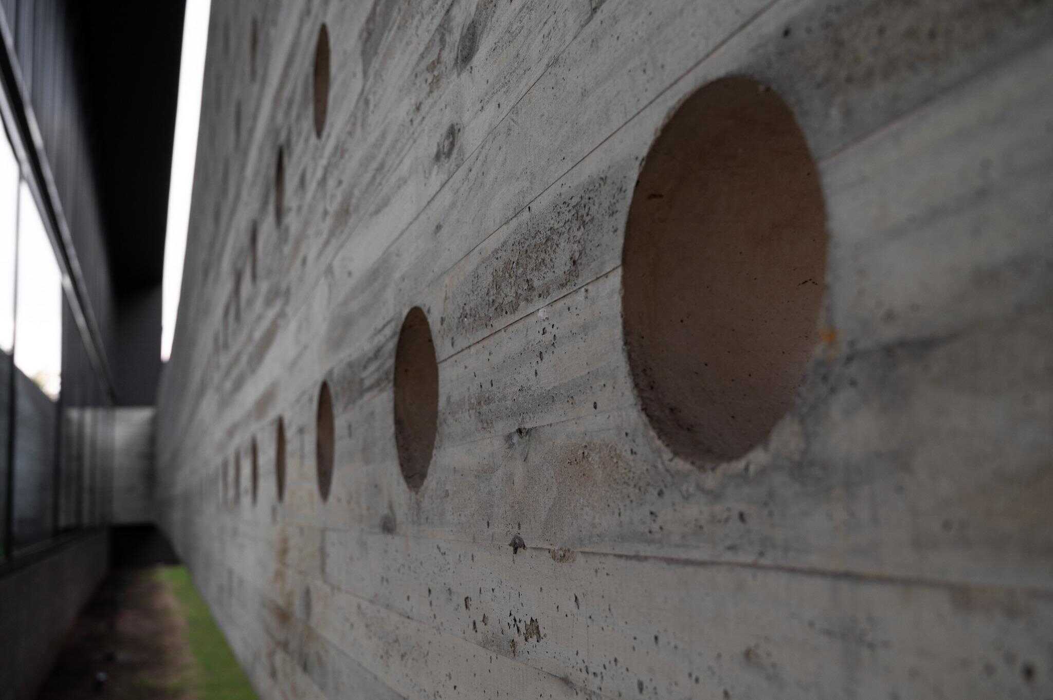 Pacheco House Perforated Concrete Detail Close-up of circular openings in the raw concrete facade of Pacheco House.