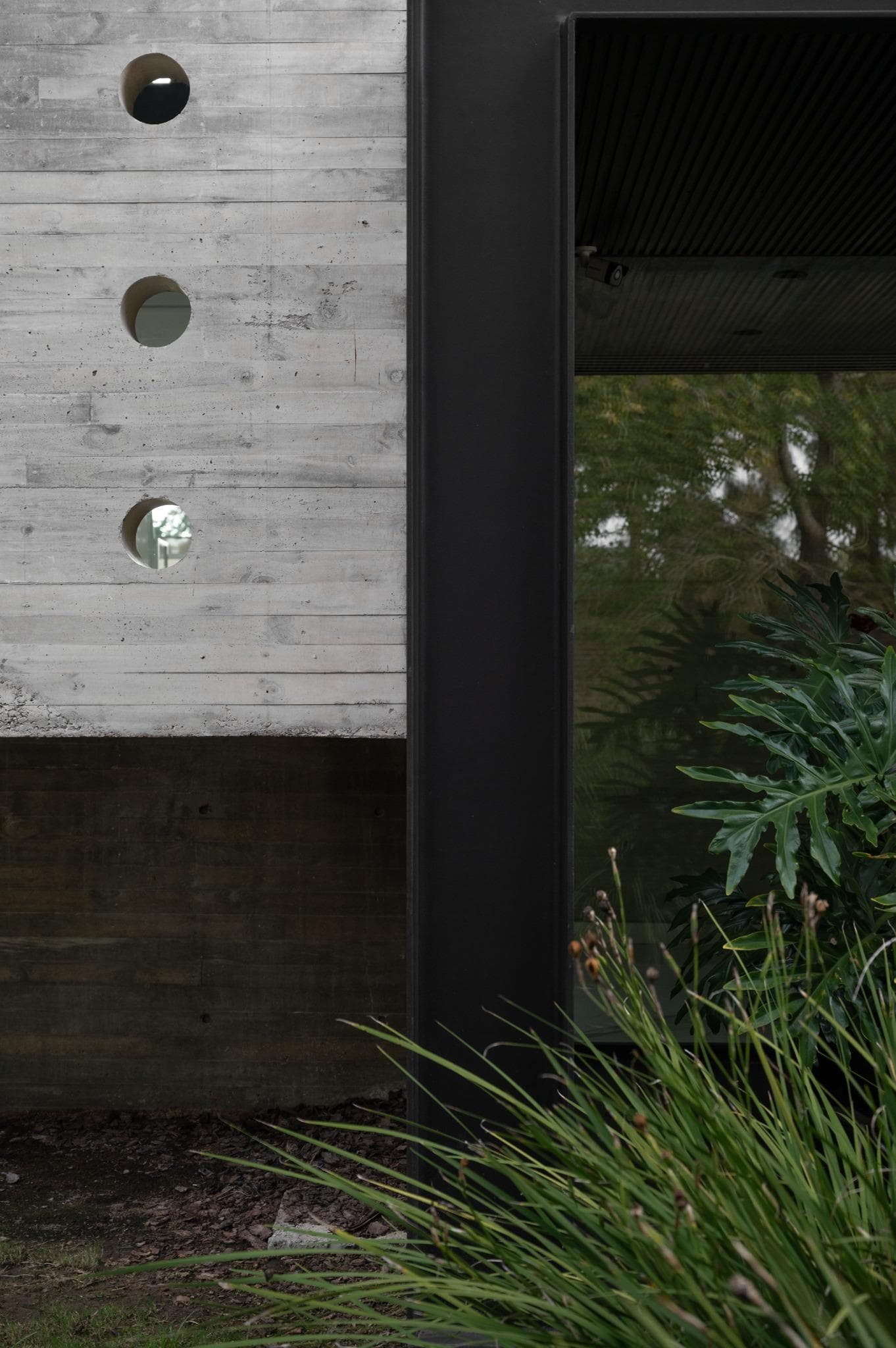 Pacheco House Perforated Wall Entrance Detail Intersection of the perforated concrete wall and dark metal frame at the entrance of Pacheco House.