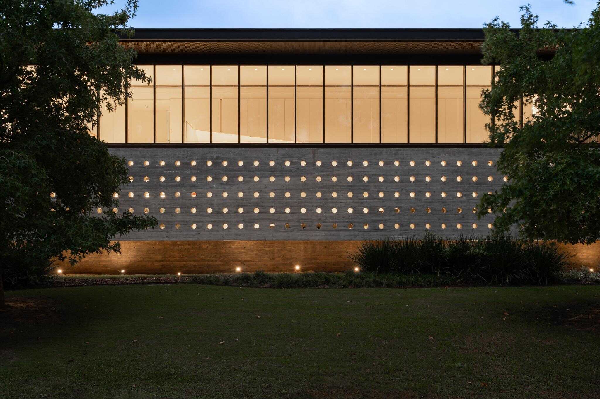 Pacheco House Perforated Wall Illuminated Nighttime view of the perforated concrete wall at Pacheco House, softly illuminated from below.