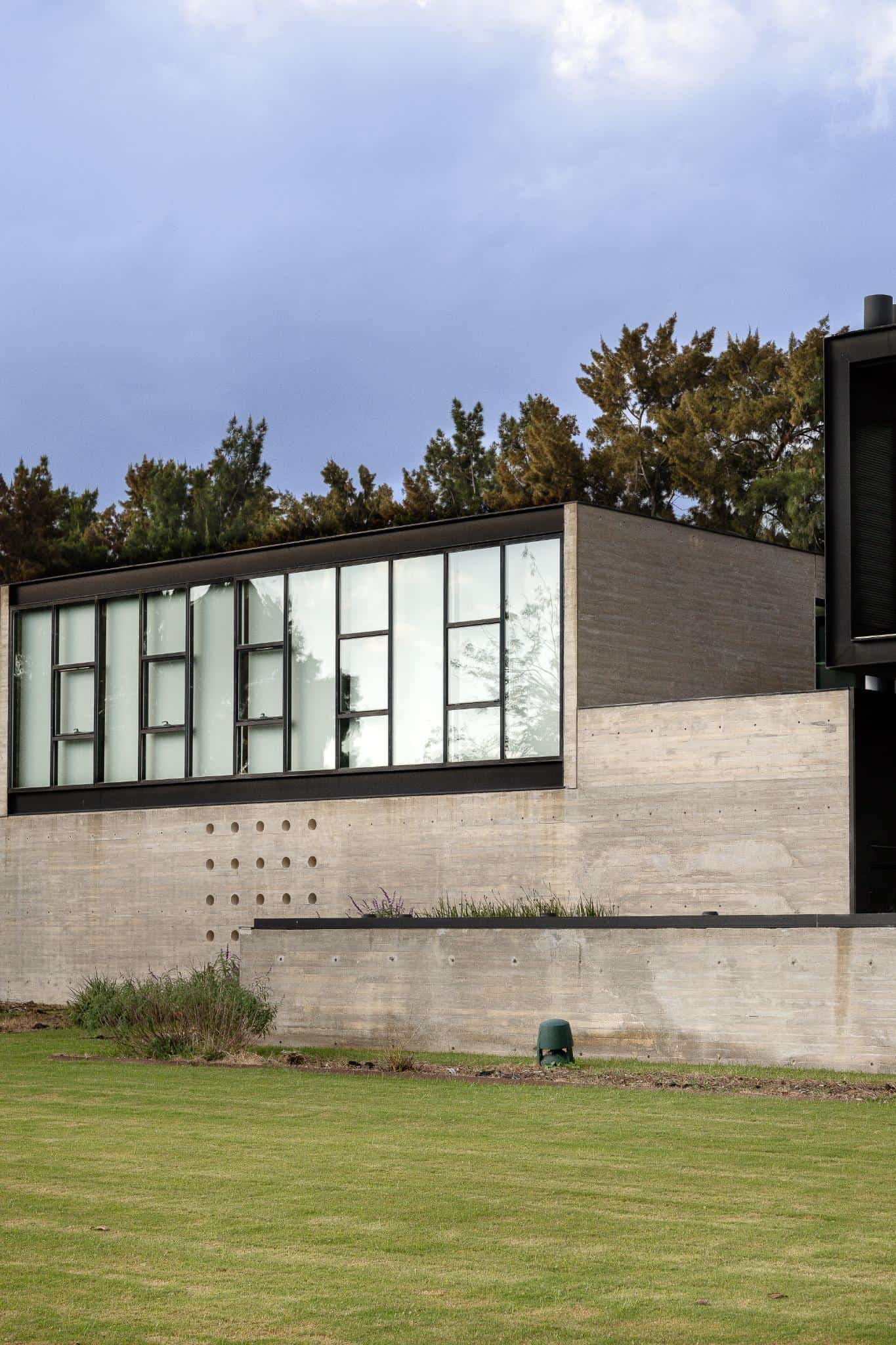 Pacheco House Private Wing Elevation Side elevation of the private wing of Pacheco House with floor-to-ceiling windows and exposed concrete.
