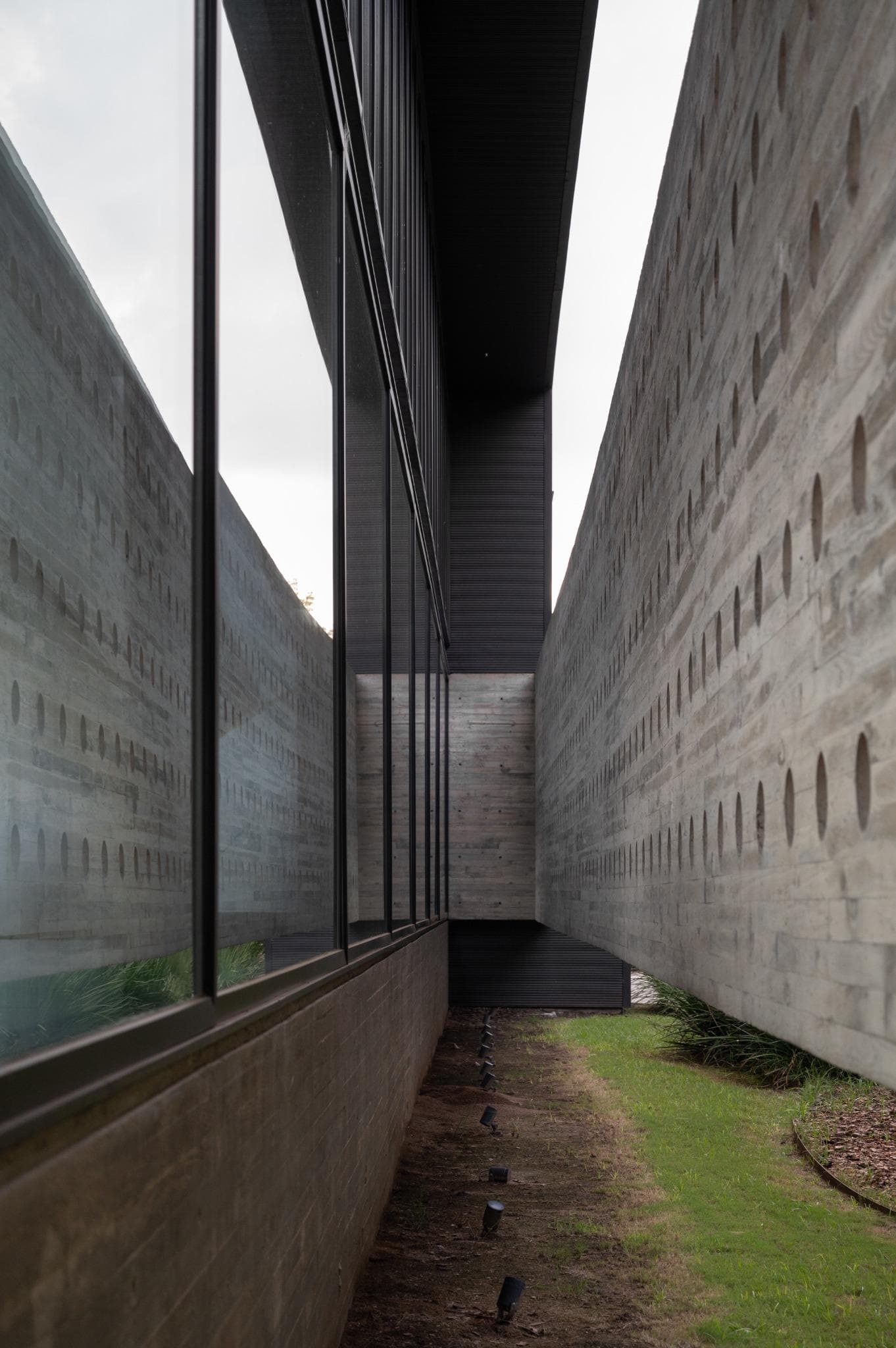 Pacheco House Punched Walls Narrow Courtyard Narrow courtyard view flanked by glass and perforated concrete walls at Pacheco House.