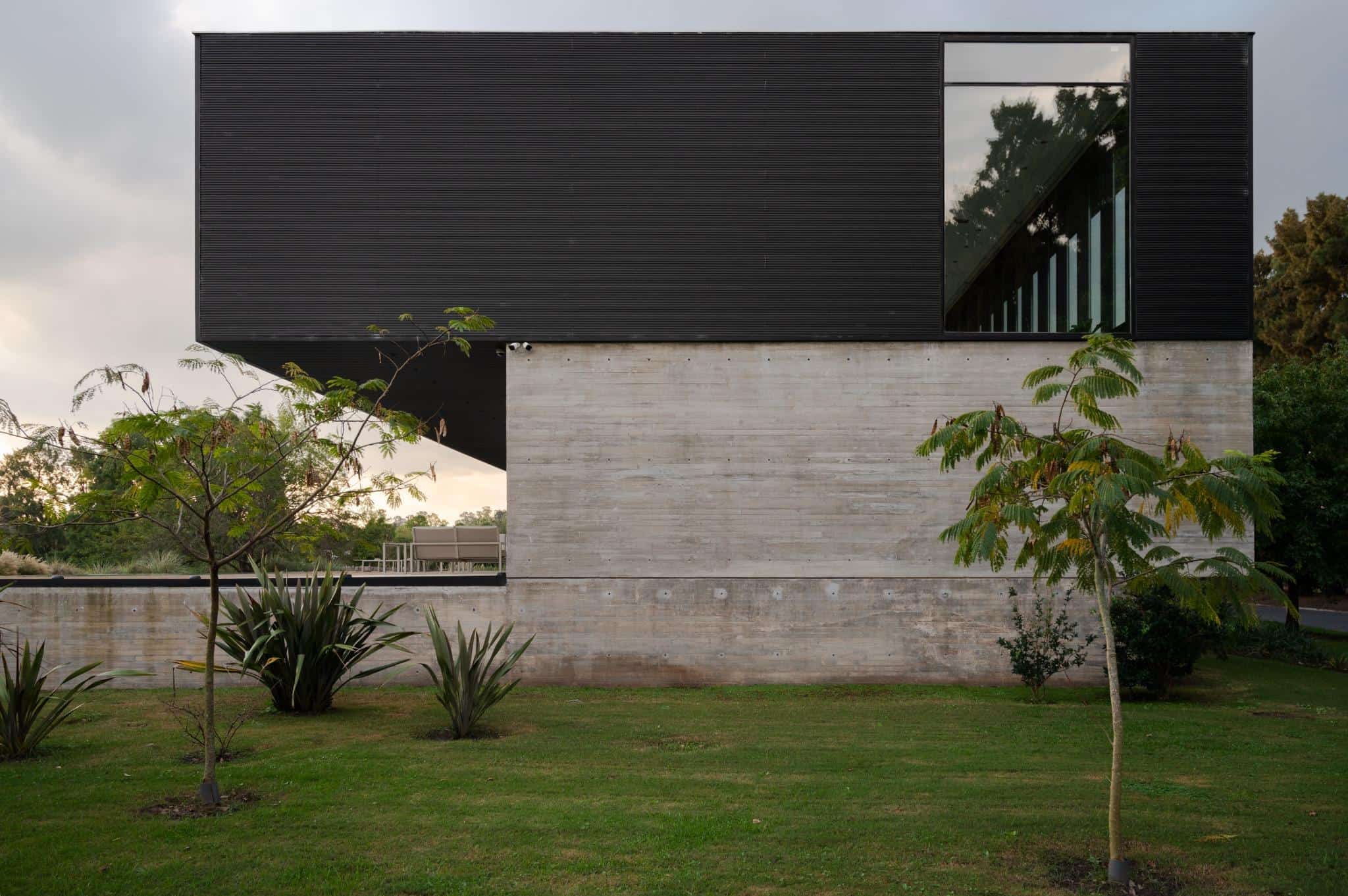 Pacheco House Side Elevation Structural Contrast Side view of Pacheco House showcasing the strong contrast between concrete and dark upper volume.