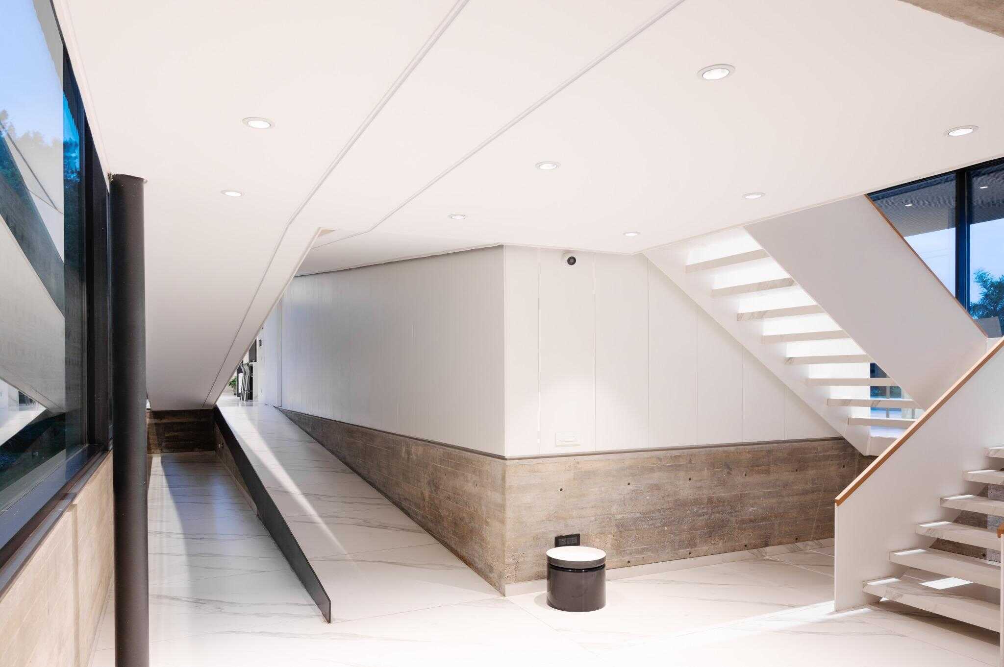 Pacheco House Staircase and Ramp Interior Interior view of Pacheco House showing clean white staircase and adjacent ramp, illuminated with recessed lighting.
