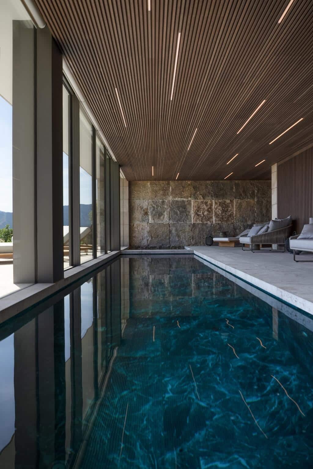 Villa Kaizen Covered Pool Reflection Reflective view of the covered pool area at Villa Kaizen surrounded by stone and glass.