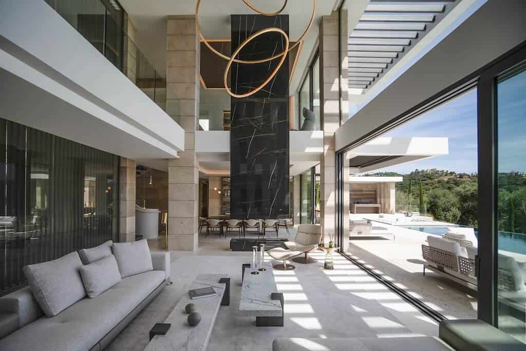 Villa Kaizen Glass Wall Living Room Double-height living room in Villa Kaizen featuring full-height glass walls and a black marble fireplace.