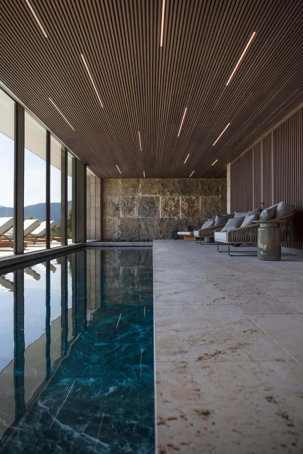 Villa Kaizen Indoor Pool Lounge Area Indoor pool lounge at Villa Kaizen with wood slatted ceiling and poolside chairs.