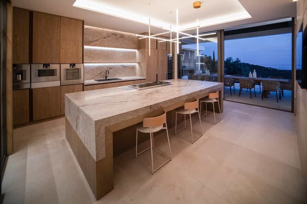 Villa Kaizen Open Kitchen Island Spacious kitchen with marble island and panoramic window views in Villa Kaizen.
