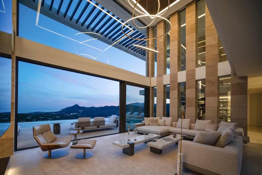 Villa Kaizen Sunset Lit Living Room Villa Kaizen's double-height living room at dusk with scenic views through glass walls.