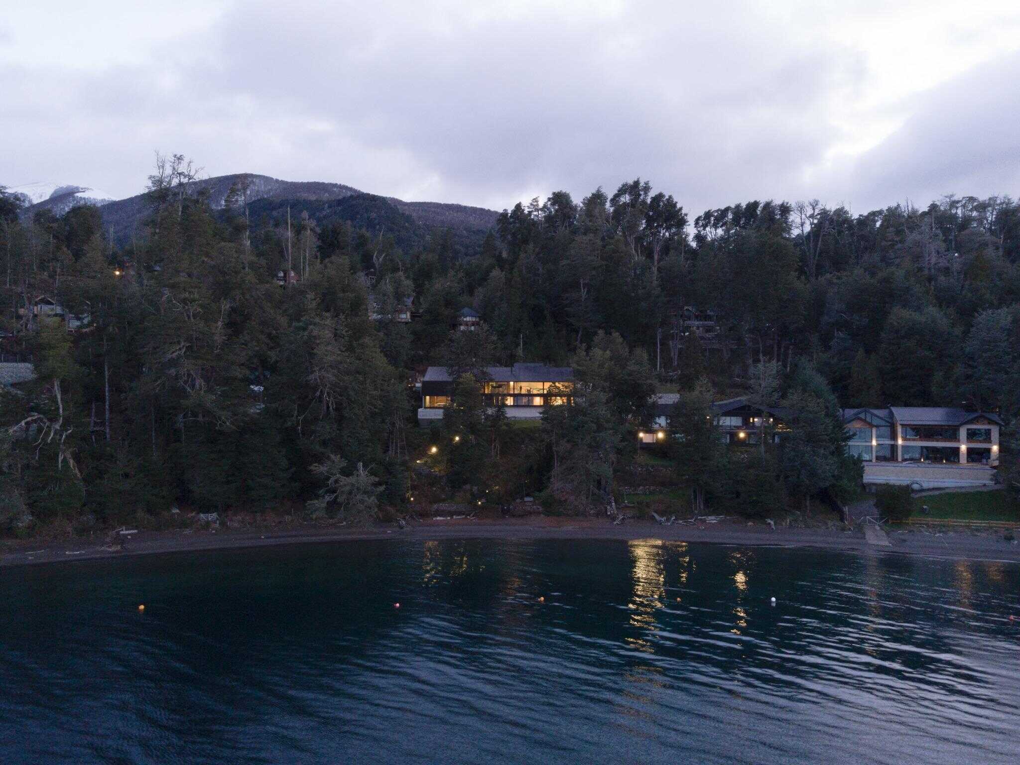 Aerial view of VLA House by A4estudio along the shoreline at dusk.