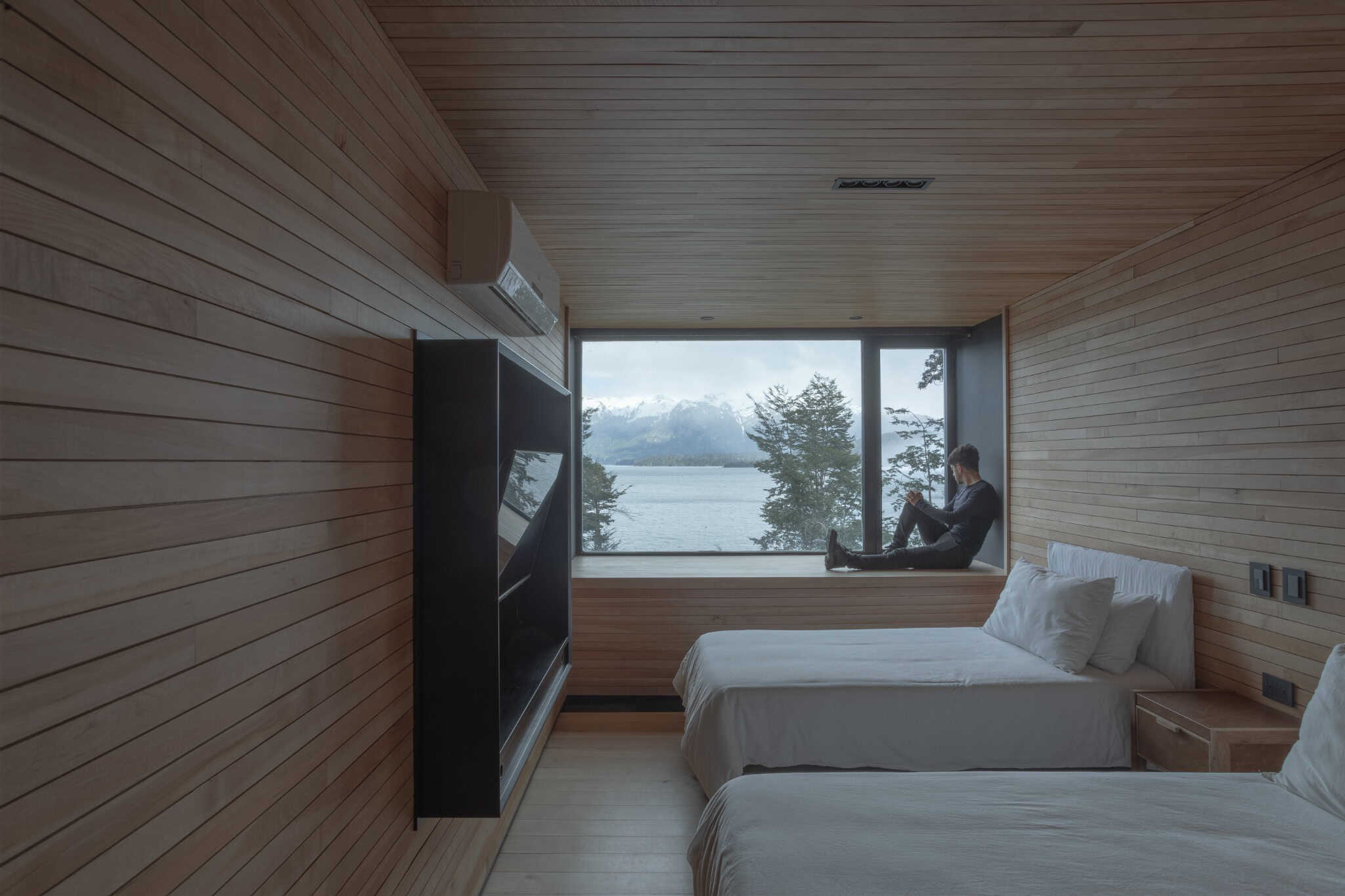 Minimalist timber-clad bedroom with mountain-view window seat at VLA House.