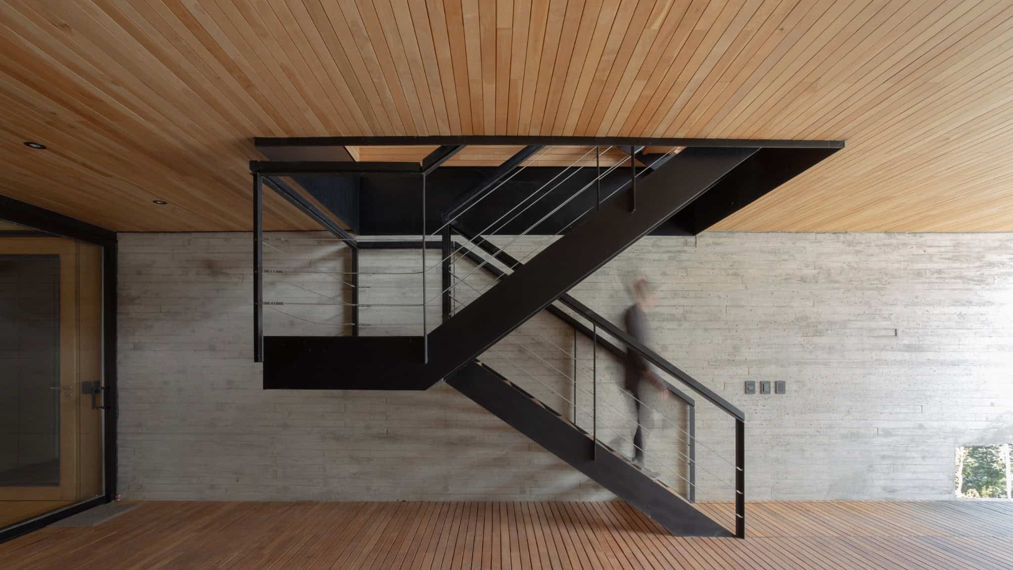 Exposed concrete stairwell and metal structure with timber ceiling.