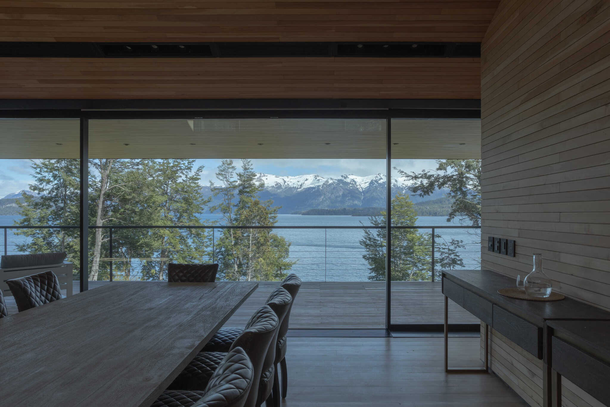 Dining area with framed panoramic view of snowcapped mountains and lake.