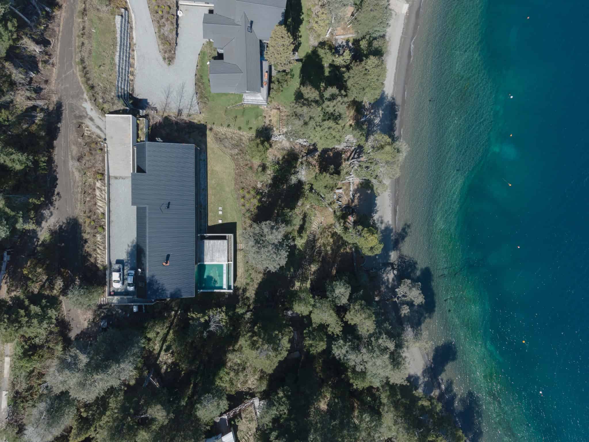 Drone view of VLA House by A4estudio facing the lakeside coastline.