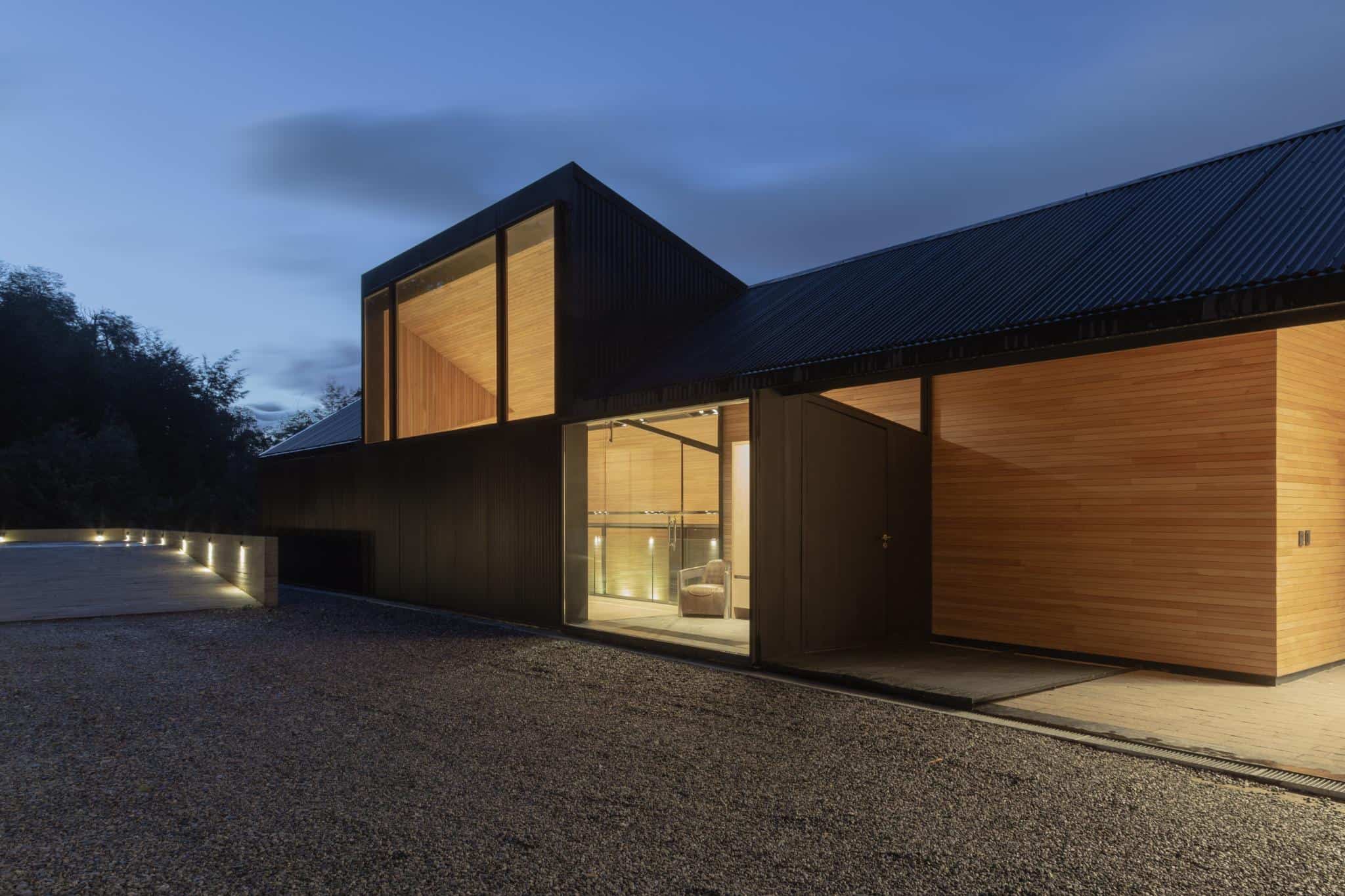 VLA House by A4estudio with evening lights along the entry deck.
