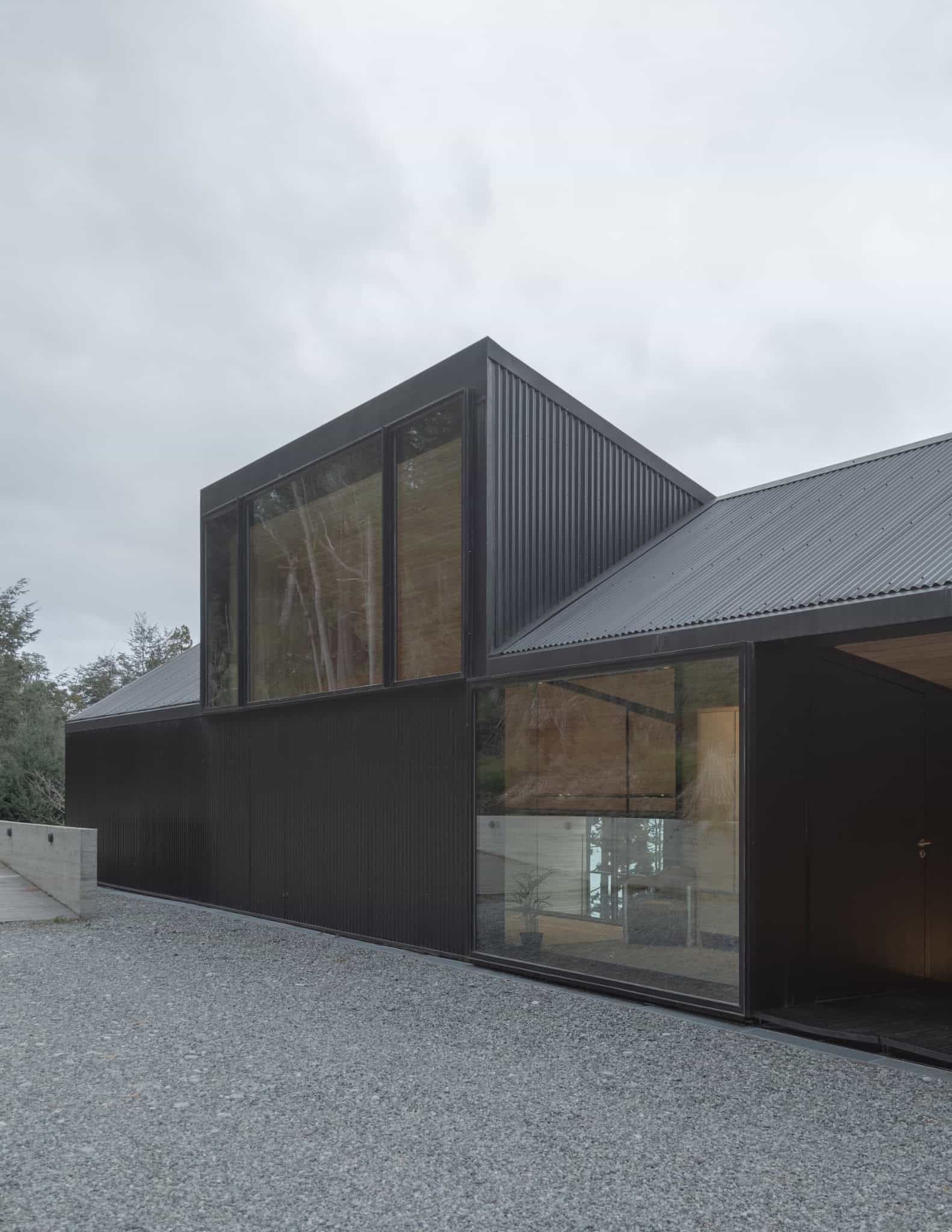 Cantilevered glass box window detail in black corrugated volume.