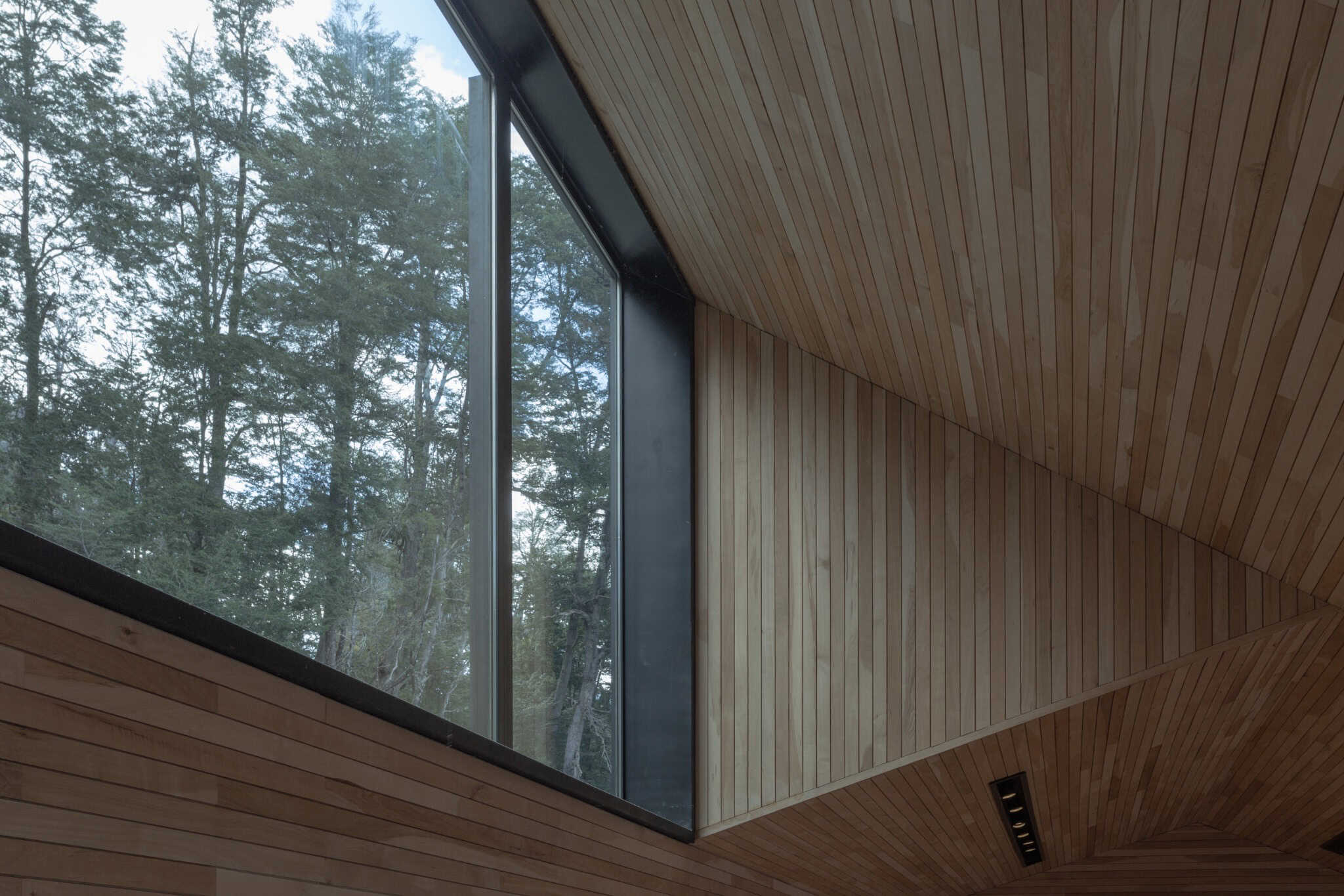 VLA House by A4estudio with dramatic forest-facing corner window and timber interior.