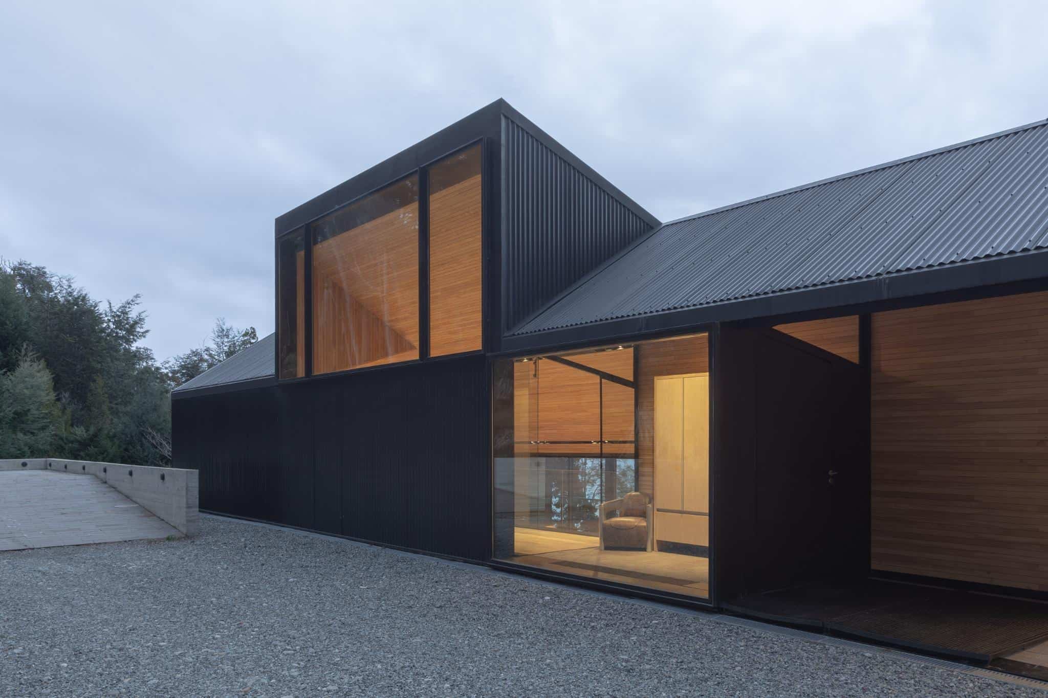 Entryway of VLA House by A4estudio featuring glass walls and warm wood interiors.