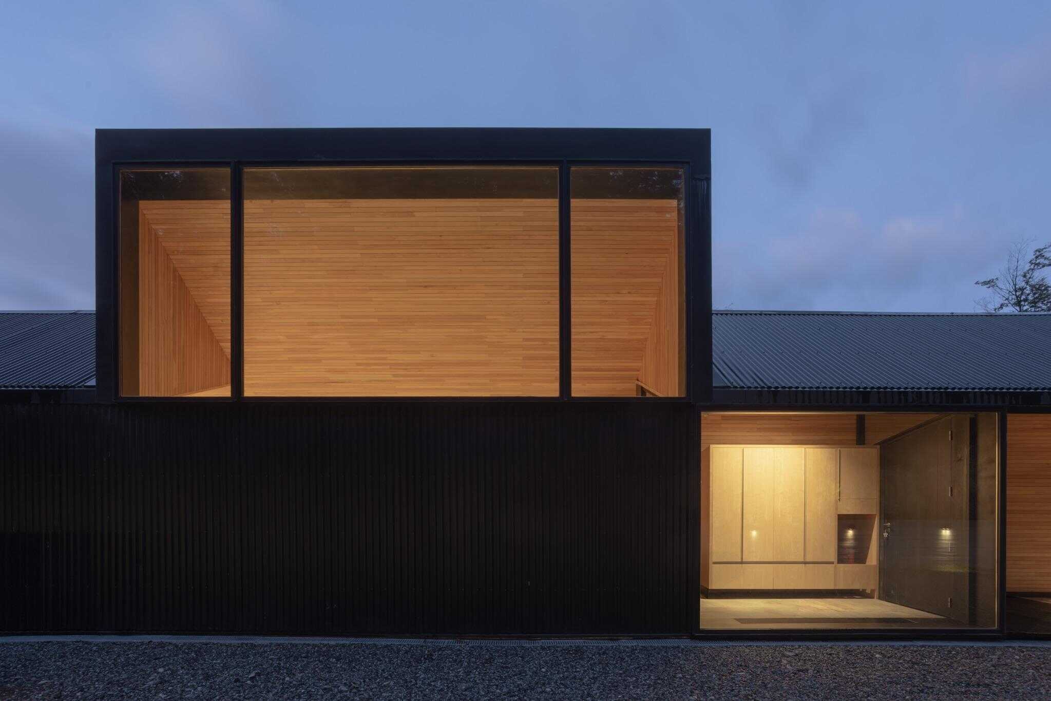 Night view of glass entry at VLA House by A4estudio with warm interior lighting.