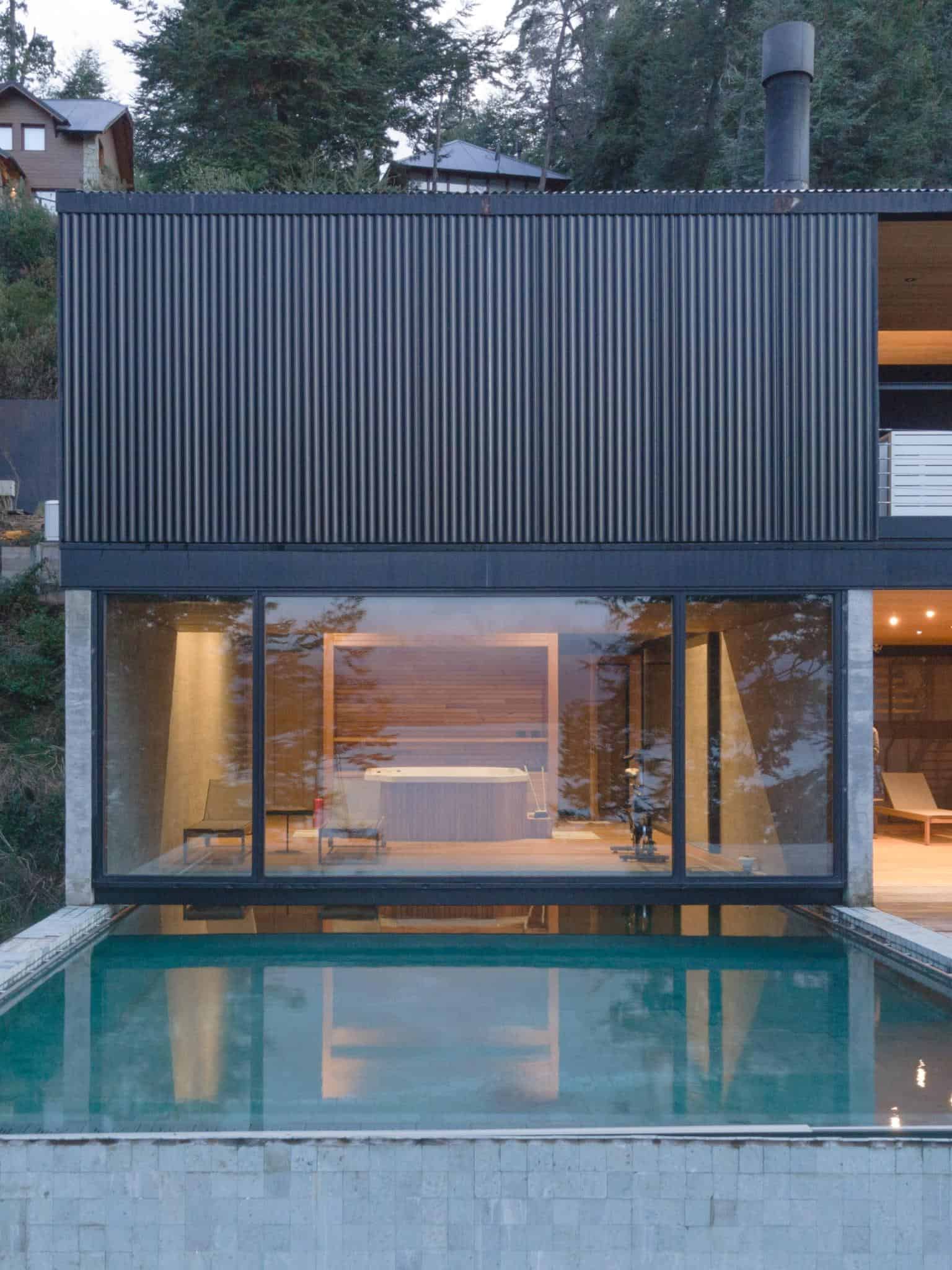 Front view of VLA House by A4estudio with glass wall revealing indoor pool.