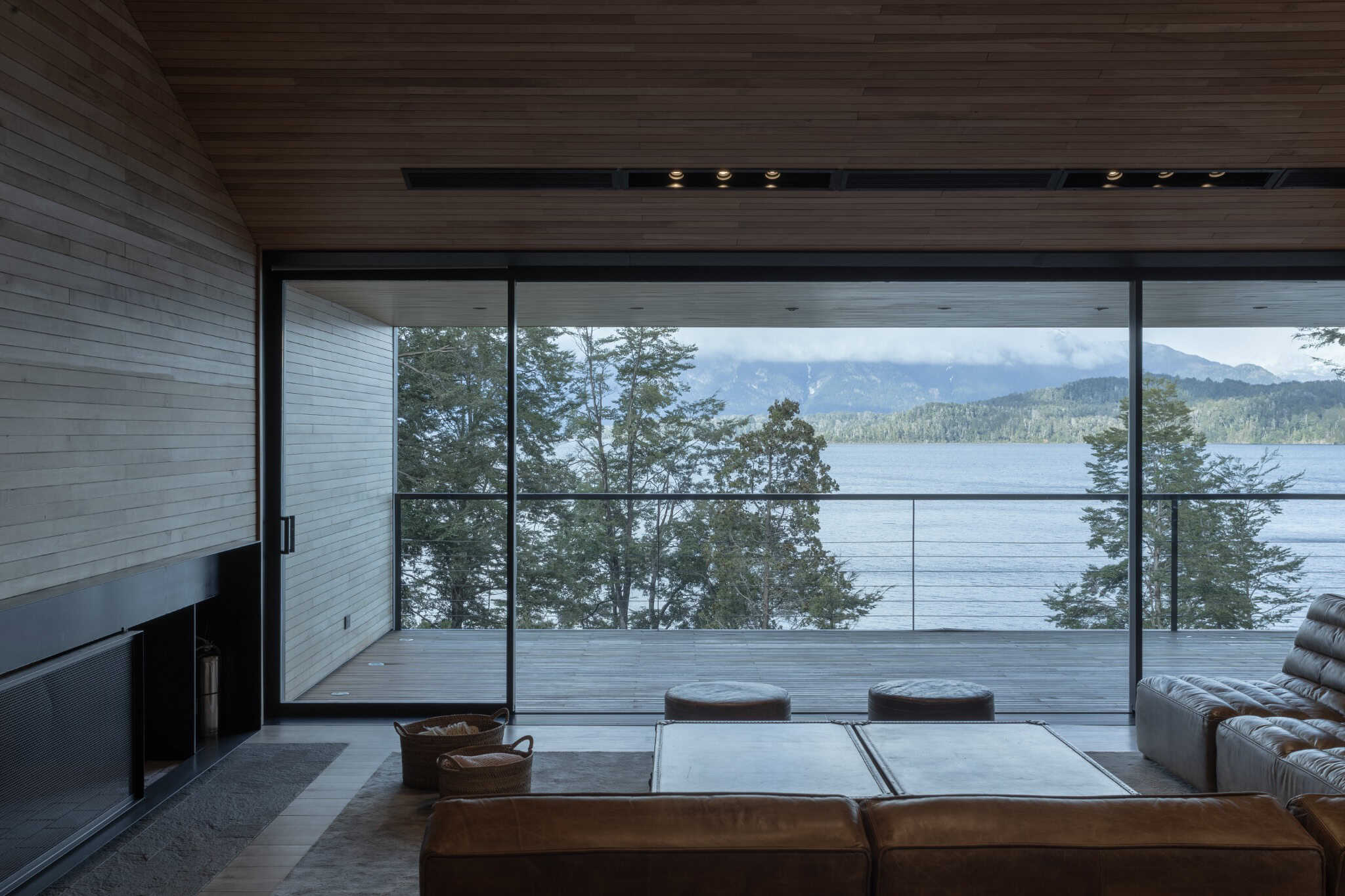 VLA House interior with full-height glazing opening to a terrace and lake view.