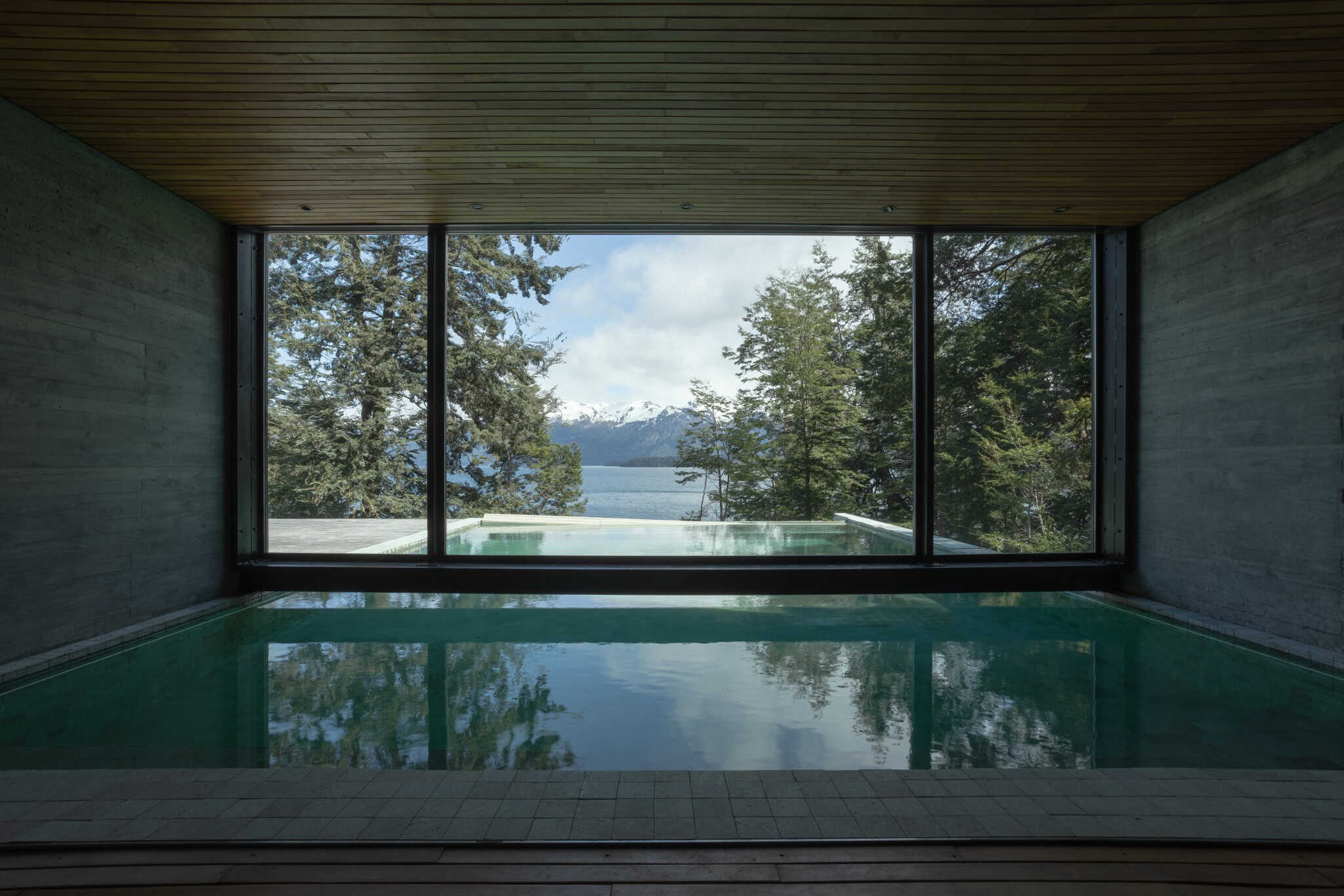 Indoor pool at VLA House by A4estudio with framed view of the Andes and lake.