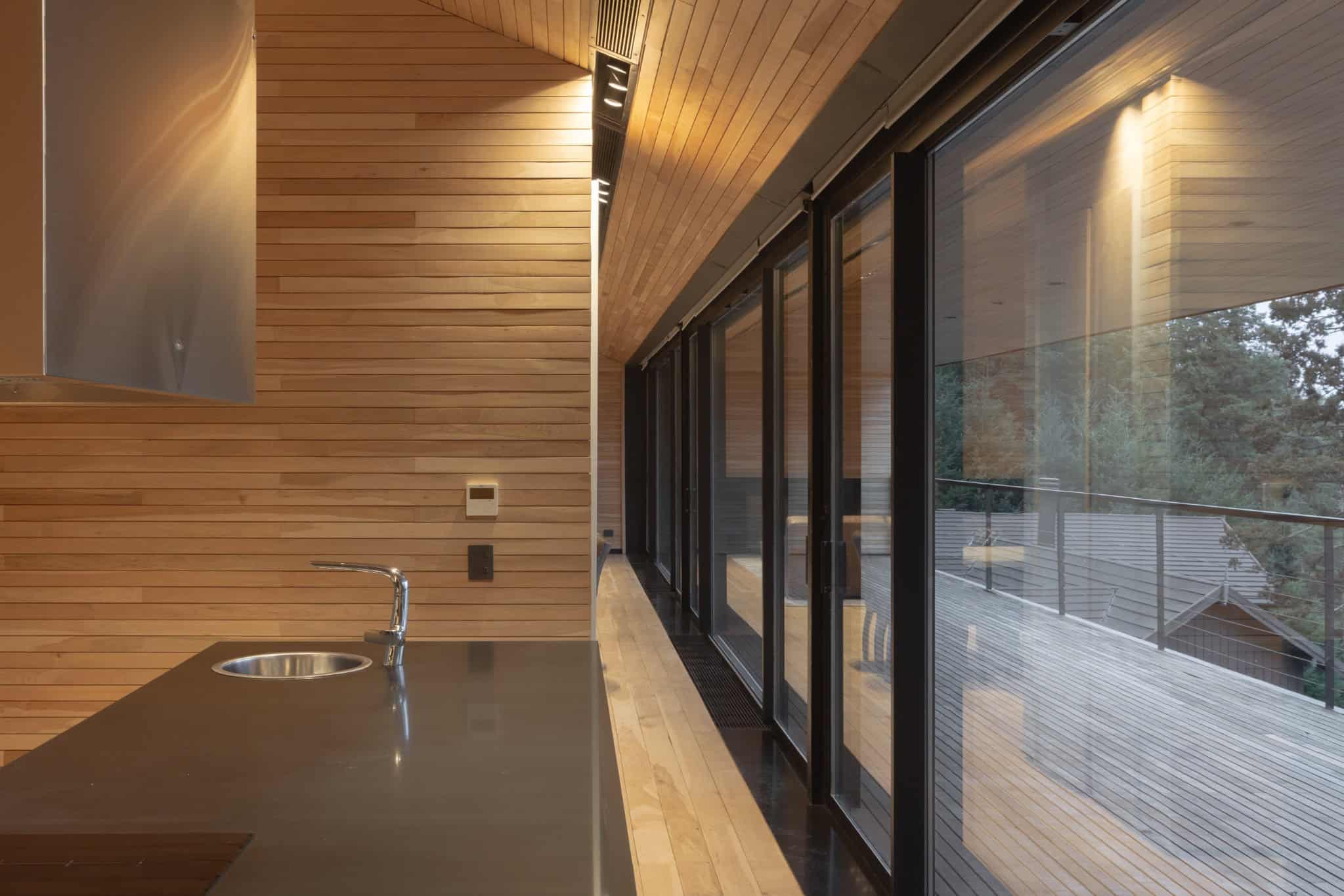 VLA House by A4estudio with kitchen featuring full-height glass wall along corridor.