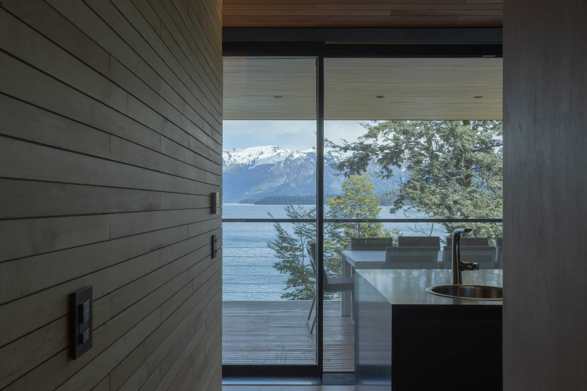 Kitchen island with lake and mountain view through glass walls at VLA House.