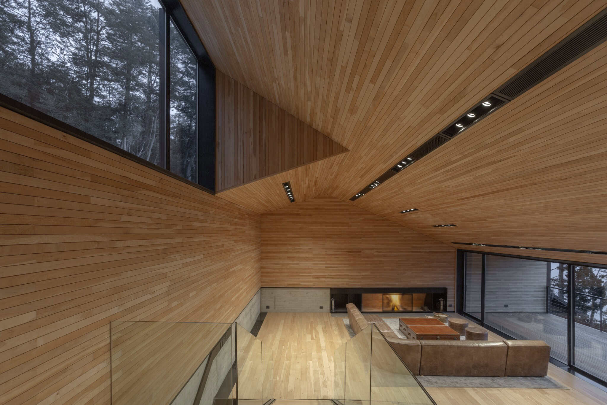 Spacious living room of VLA House with warm wood ceiling and integrated lighting.
