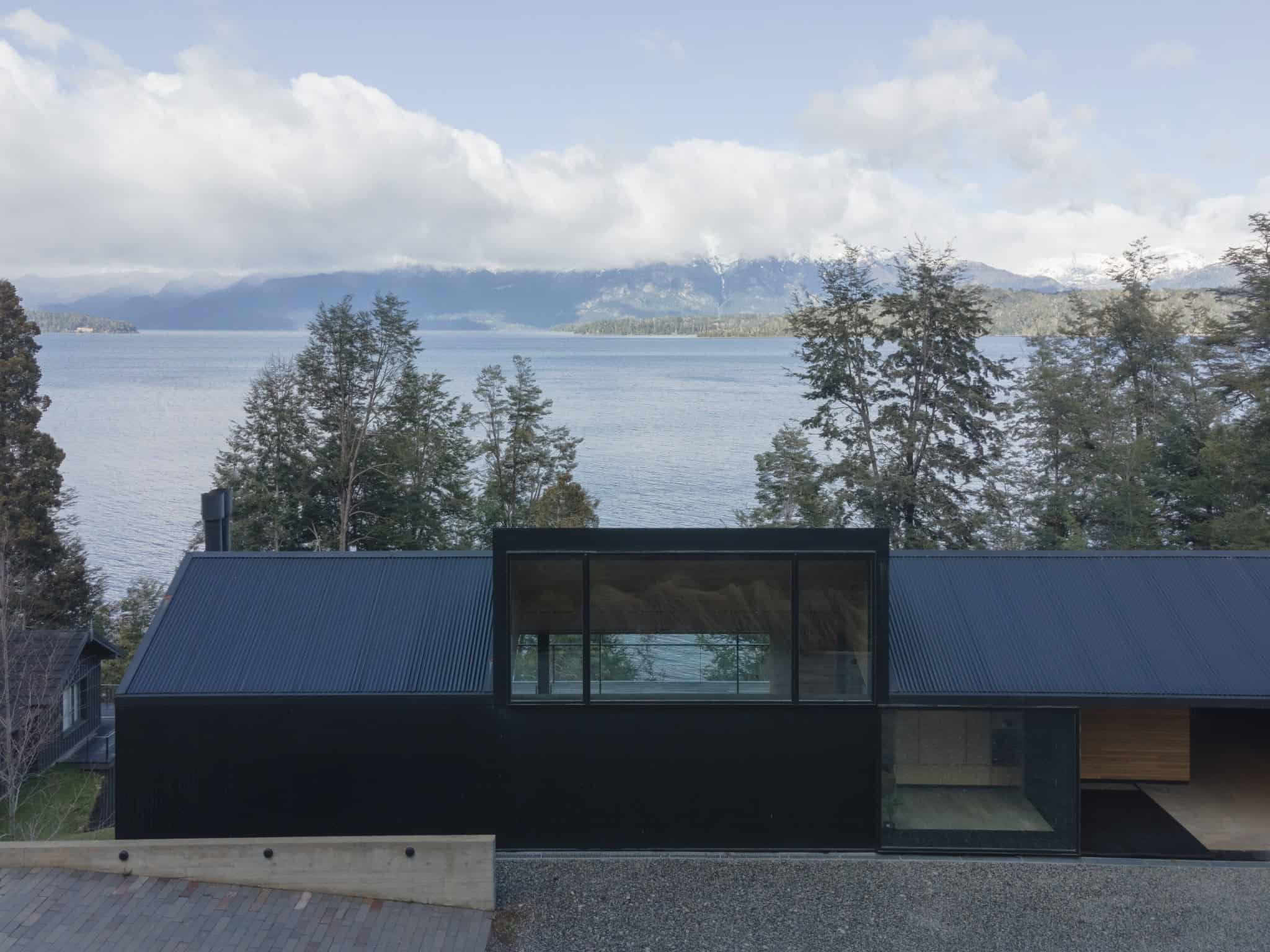 Modern black cabin of VLA House overlooking a panoramic waterfront landscape.